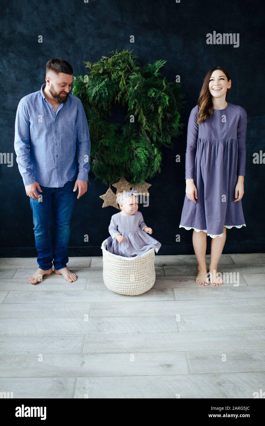 Une famille de trois sur le fond du mur du nouvel an en robes bleues. Banque D'Images