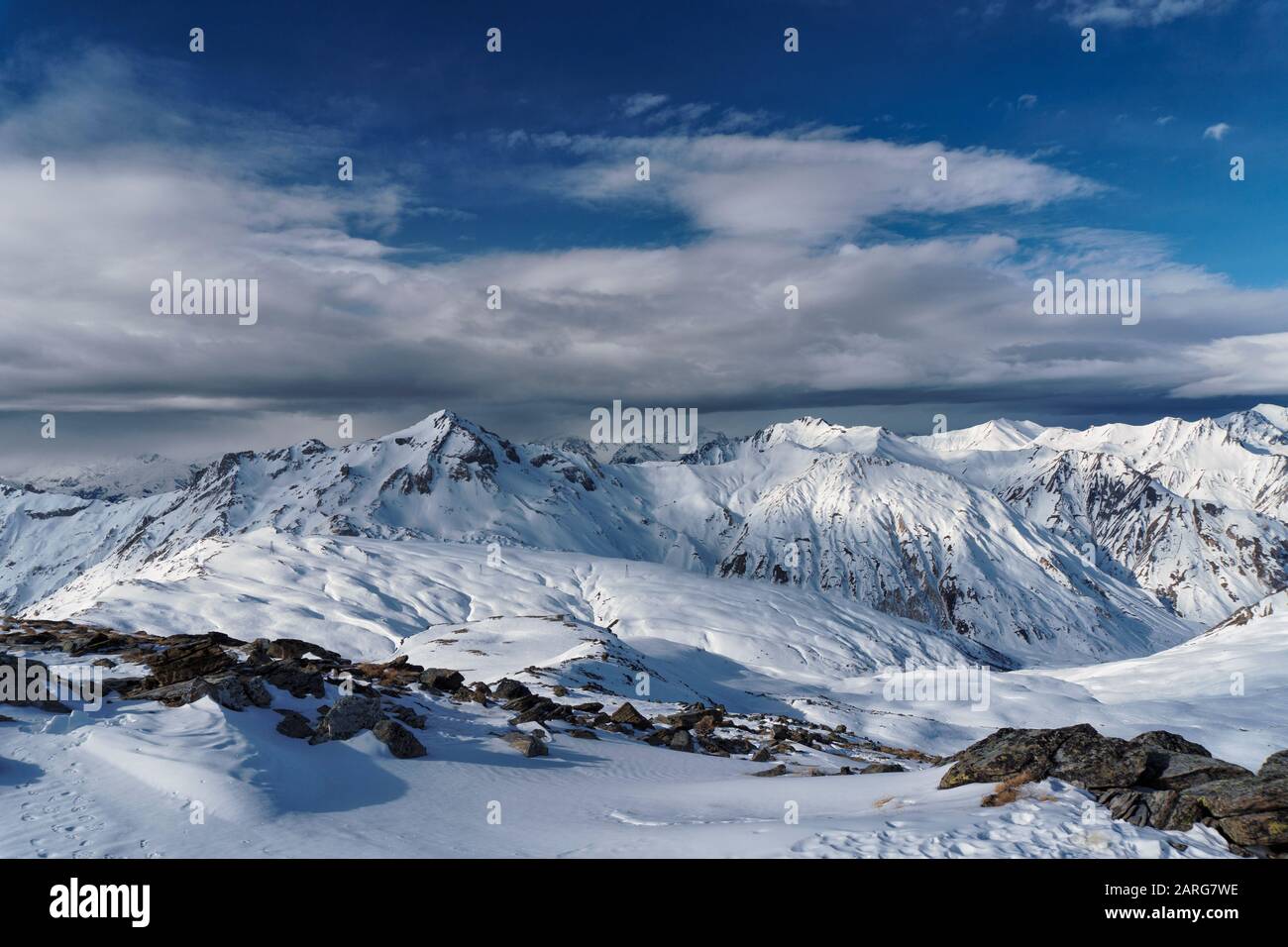 Vue du sommet de la masse dans la station française des Menuires à travers les alpes. Une banque de cloud se trouve au-dessus des pics éloignés. Banque D'Images