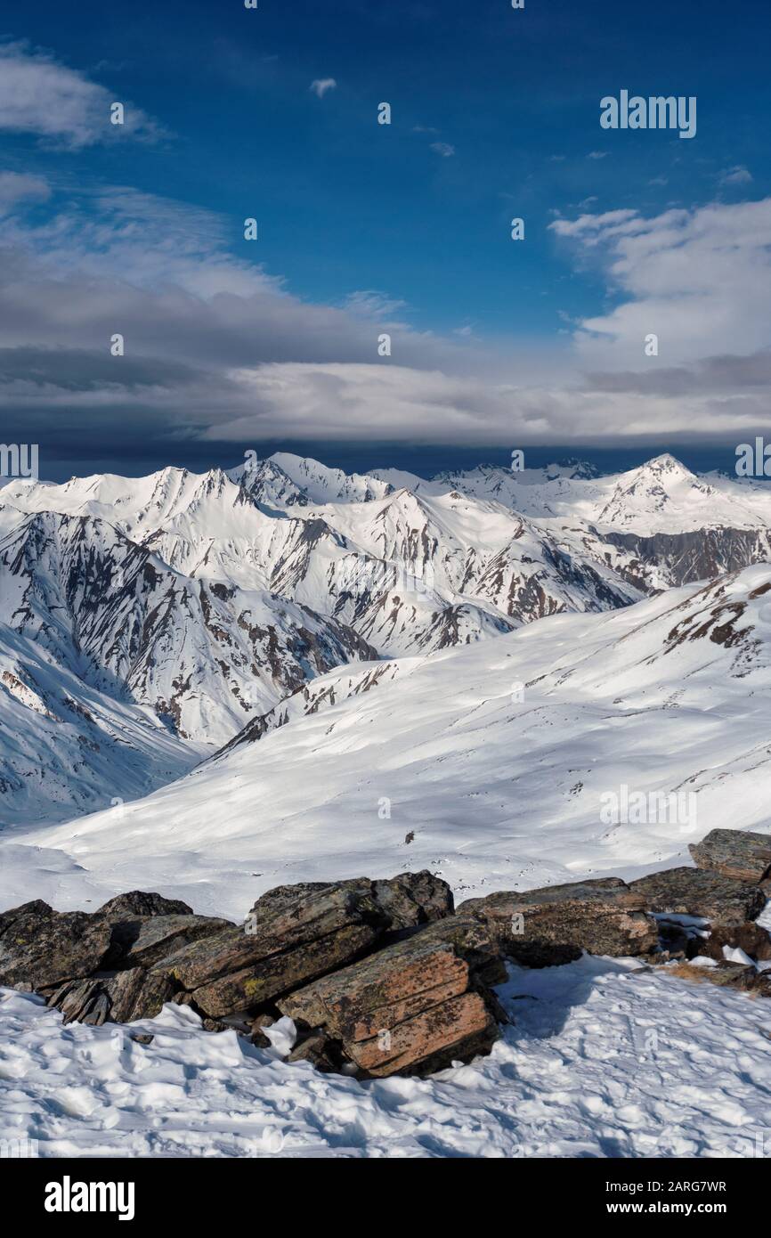 Vue du sommet de la masse dans la station française des Menuires à travers les alpes. Une banque de cloud se trouve au-dessus des pics éloignés. Banque D'Images