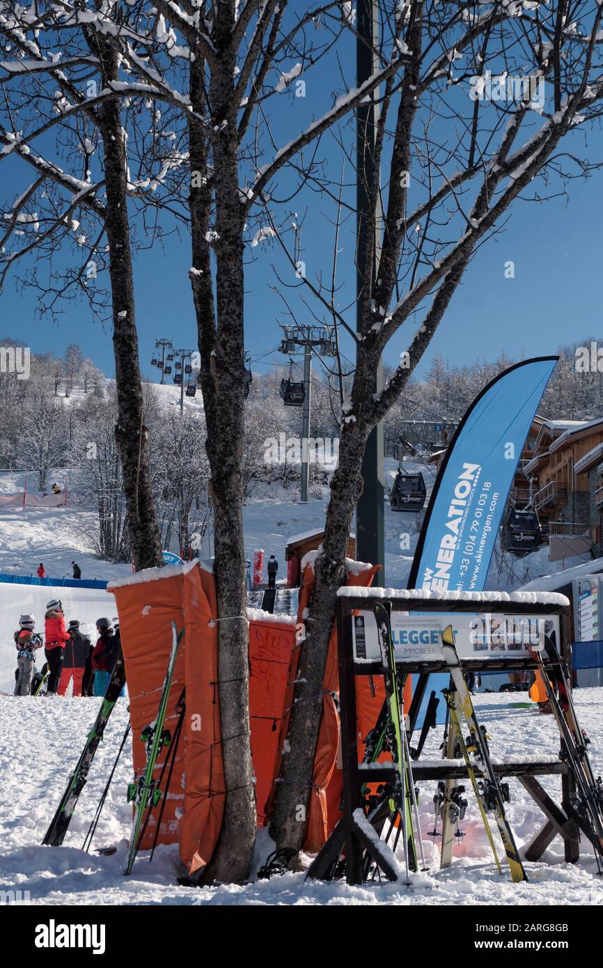 Les skis penchant sur un rack à l'extérieur d'un restaurant sous un ciel bleu clair dans la station de ski de St Martin de Belleville dans les alpes françaises Banque D'Images