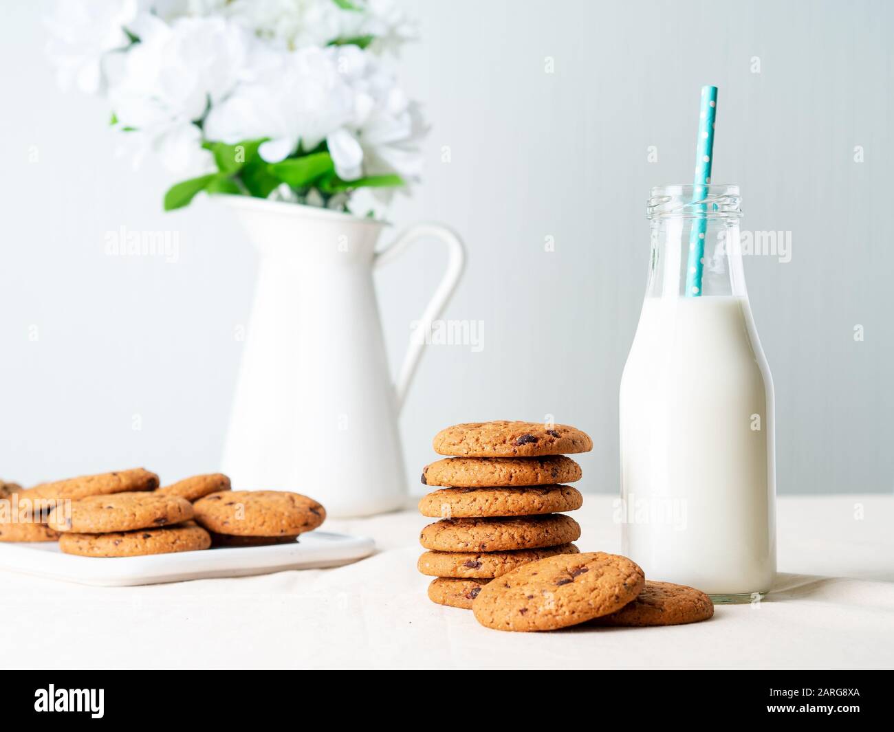 Biscuits au chocolat et lait en bouteille, encas sains. Fond clair, mur gris clair Banque D'Images