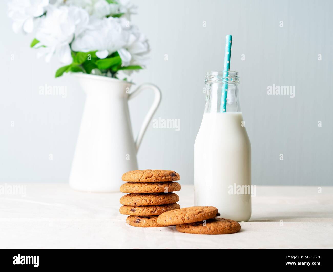 Biscuits au chocolat et lait en bouteille, encas sains. Fond clair, mur gris clair Banque D'Images