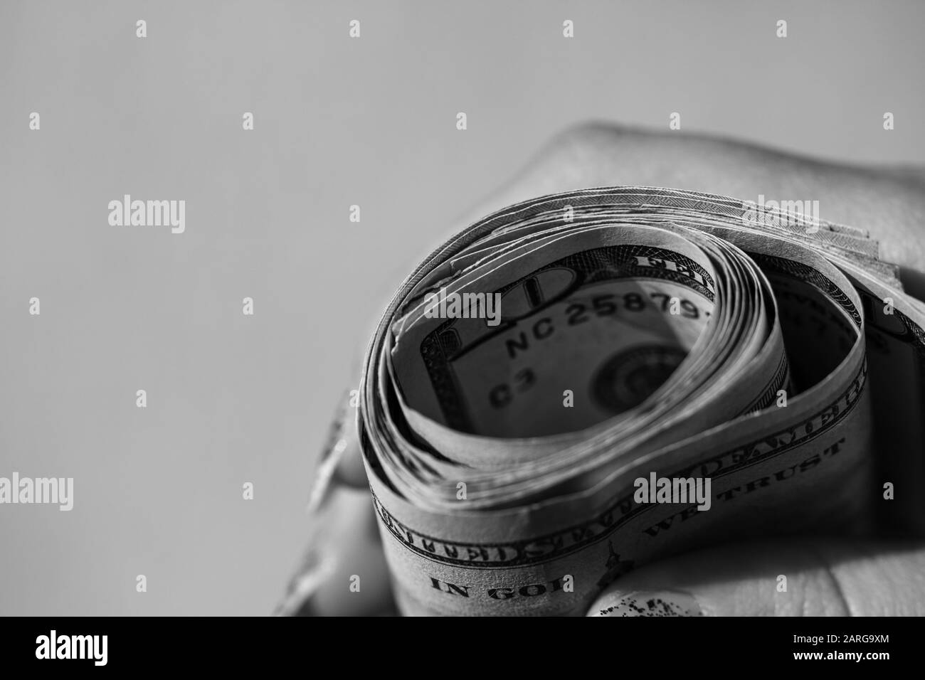 Main tenant de l'argent roulé, tenant des billets en dollars américains sur un fond flou, monnaie américaine . Banque D'Images