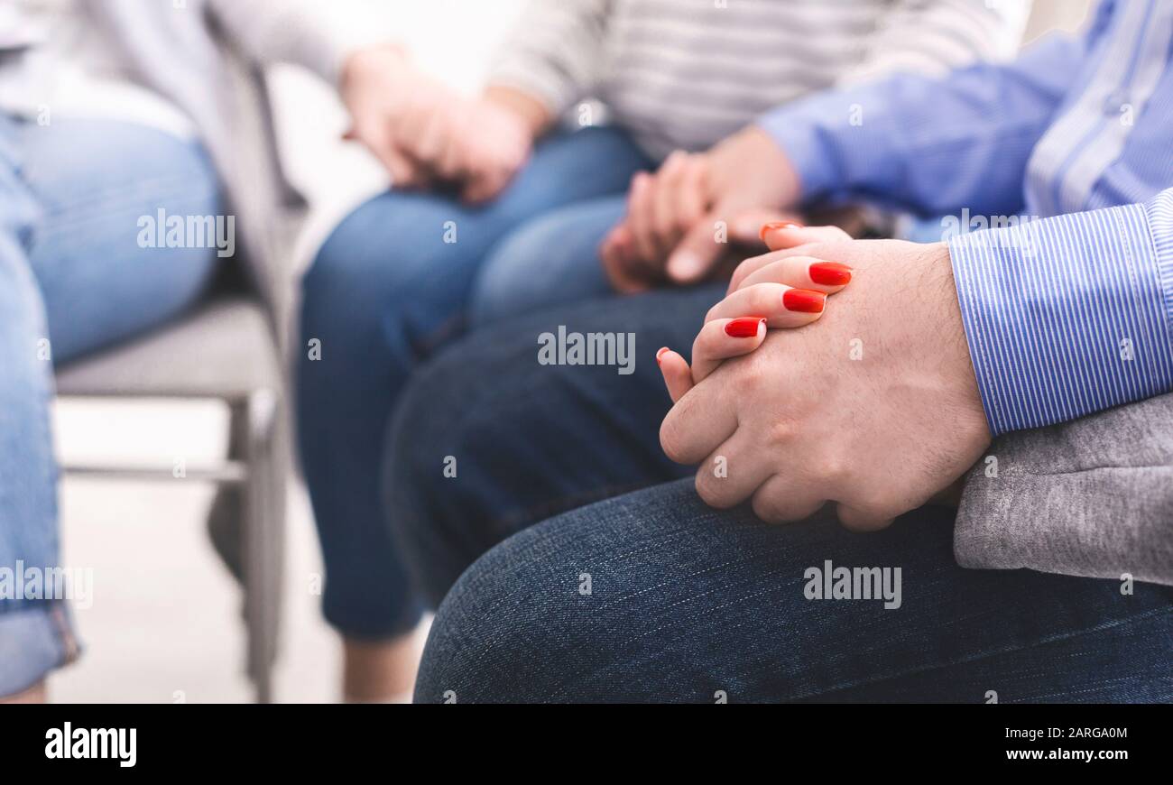 Les personnes qui tiennent les mains tout en étant assis dans un cercle de confiance pendant la séance de thérapie Banque D'Images