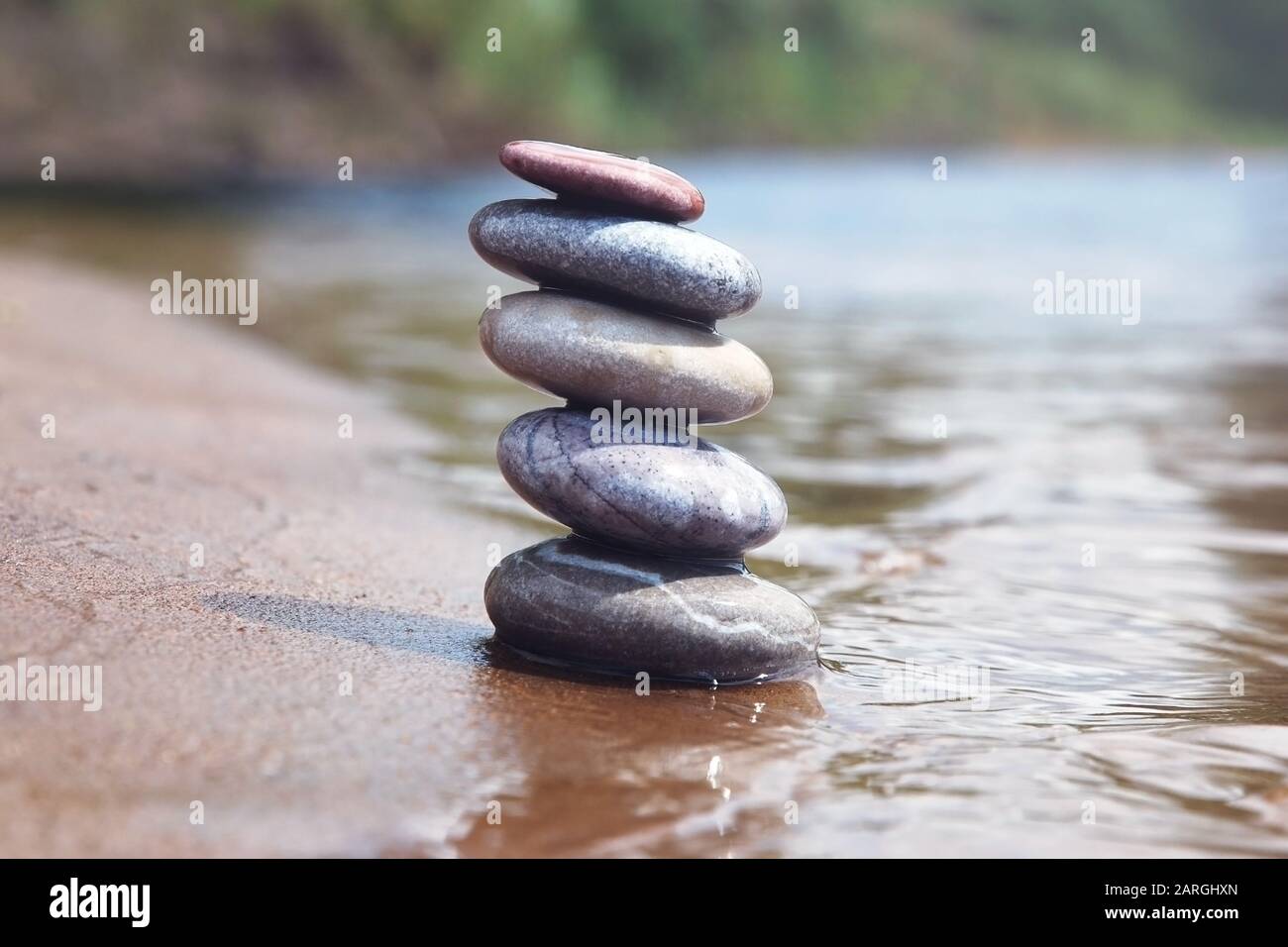 Pile de pierres de galets d'équilibrage sur le bord du sable et de l'eau. Symbole zen sur fond de nature flou. Banque D'Images