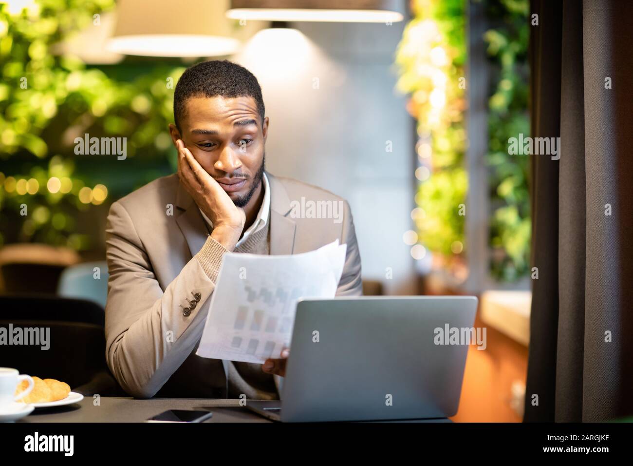 Afro homme d'affaires regardant des documents avec des graphiques Banque D'Images