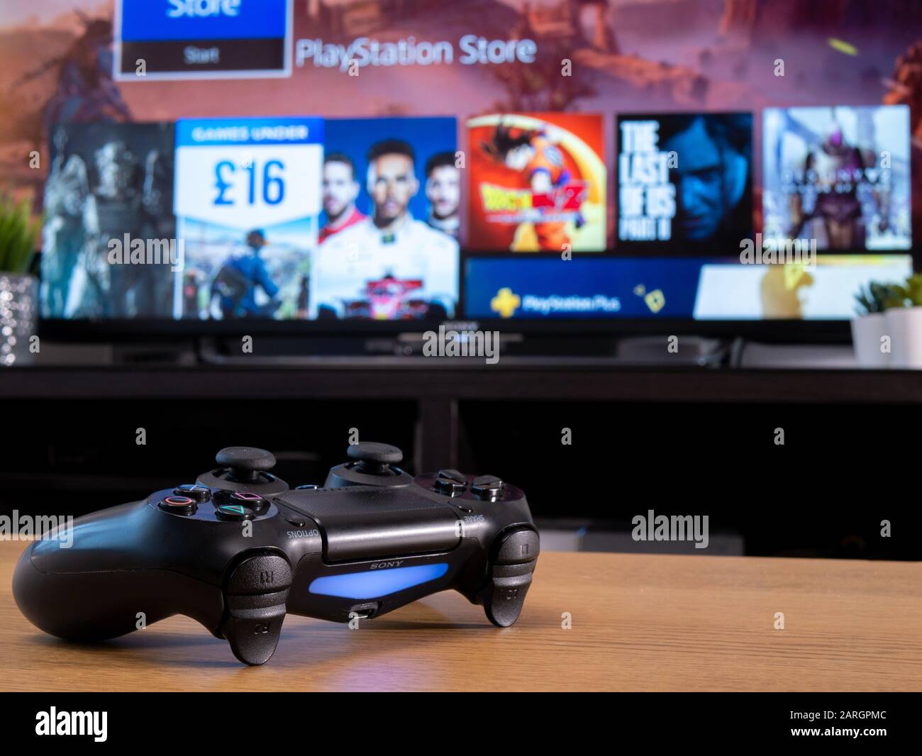 Royaume-Uni, janvier 2020 : manette sans fil Dualshock 4 de Sony avec  boutique En ligne Playstation sur l'écran de télévision derrière Photo  Stock - Alamy