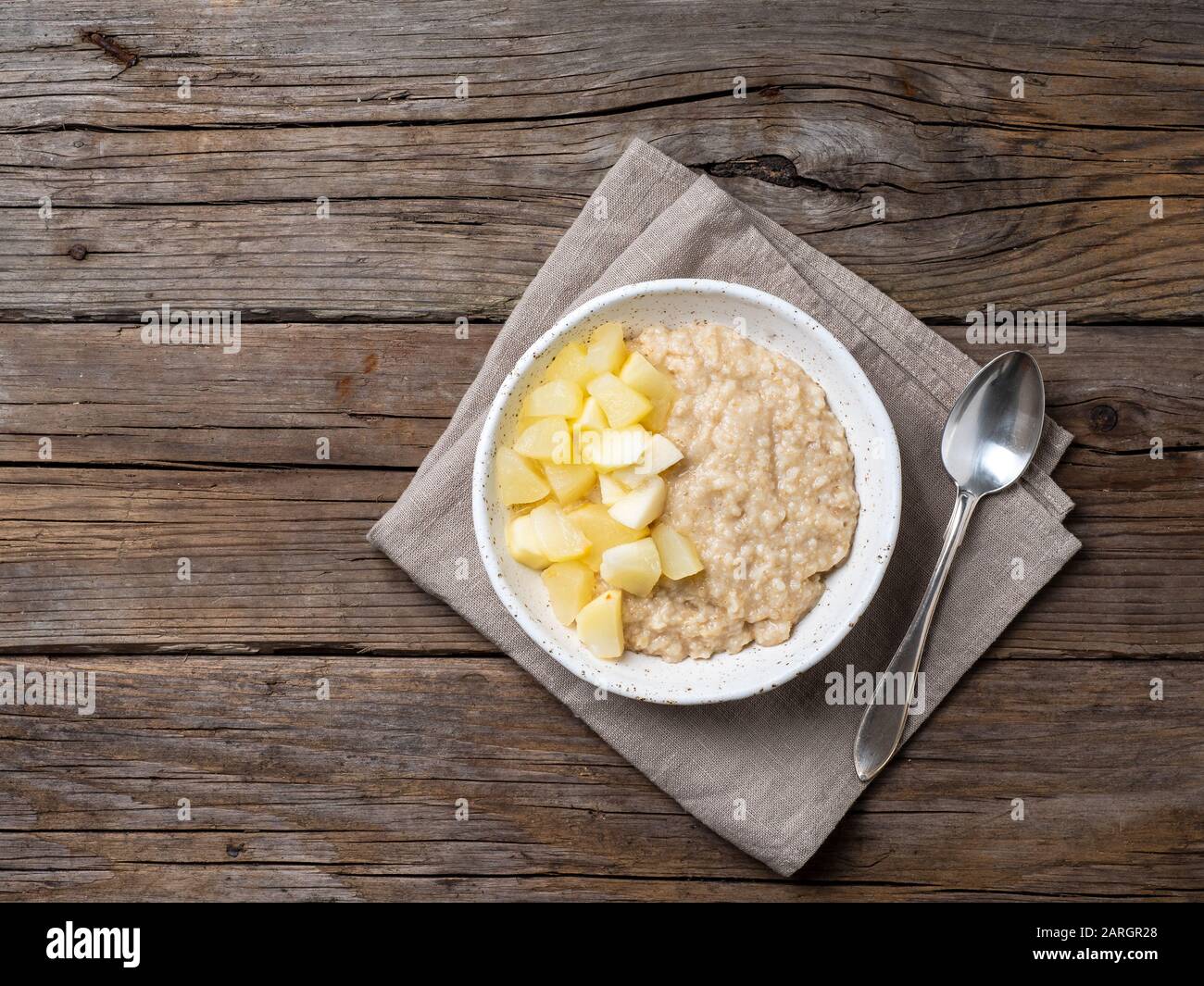 Grand bol de flocons d'avoine savoureux et sains avec pomme pour le petit déjeuner, repas du matin. Vue sur le dessus, vue rapprochée, table rustique en bois Banque D'Images