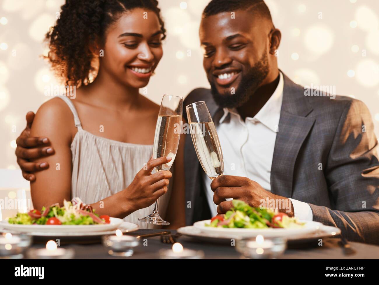 Un jeune couple afro se dégustant avec du champagne tout en dînant Banque D'Images