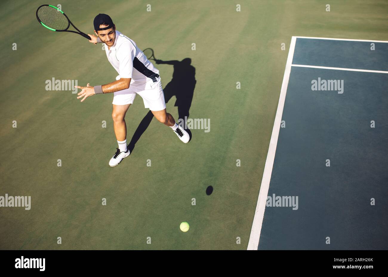 Un jeune joueur de tennis masculin concentré qui frappe le front depuis la ligne de base. Joueur de tennis jouant à un match sur le terrain dur. Banque D'Images