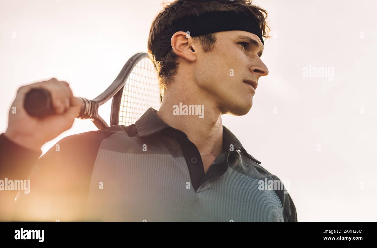 Gros plan d'un joueur de tennis professionnel debout dehors une journée ensoleillée. Joueur de tennis masculin avec raquette à l'extérieur. Banque D'Images