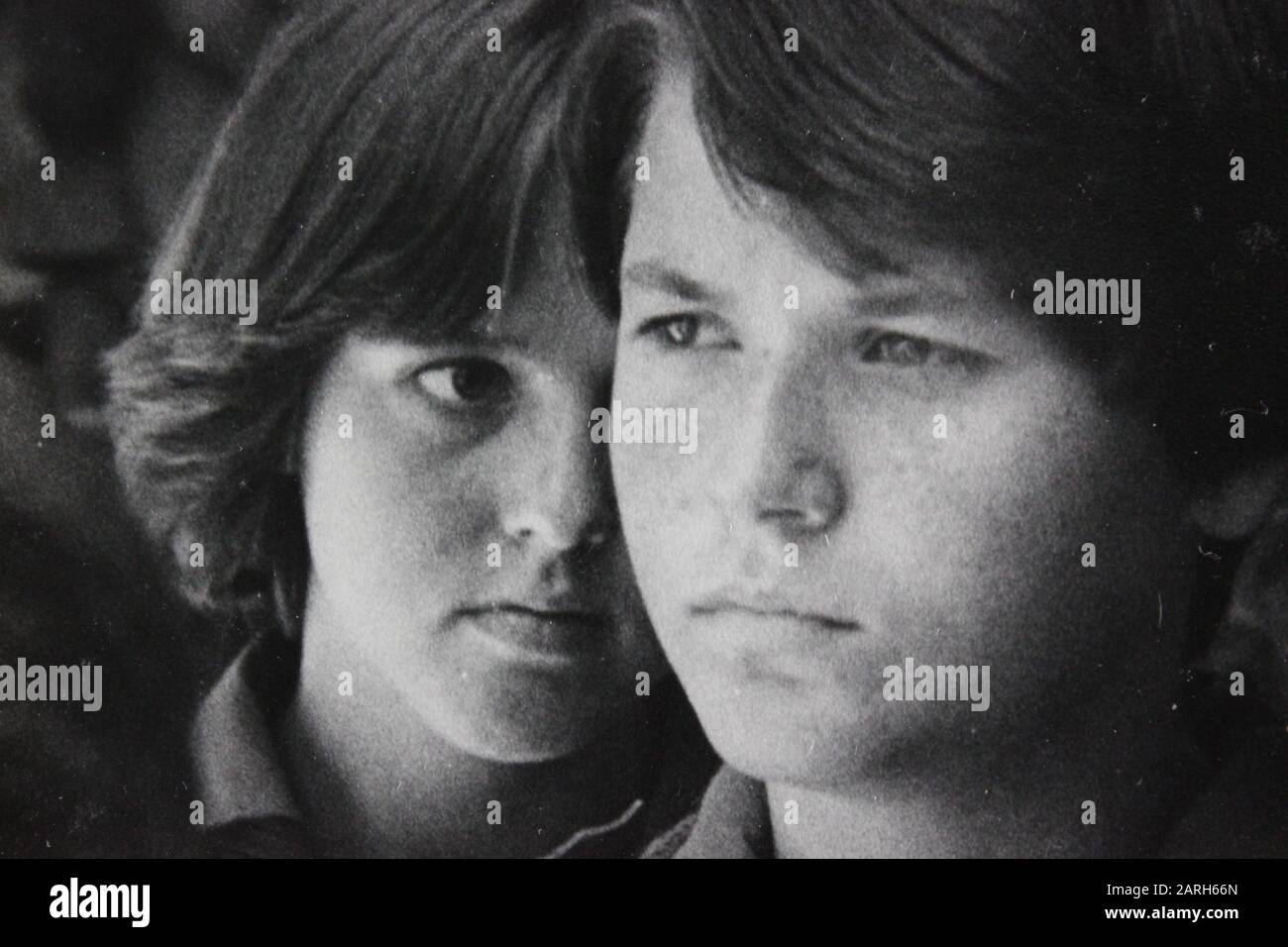 Fine photographie d'époque noir et blanc des années 1970 d'un adolescent chuchotant à un autre adolescent suspect Banque D'Images