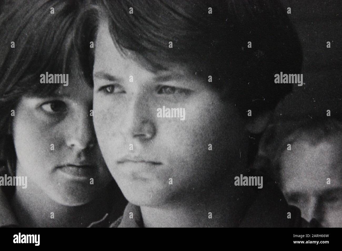 Fine photographie d'époque noir et blanc des années 1970 d'un adolescent chuchotant à un autre adolescent suspect Banque D'Images