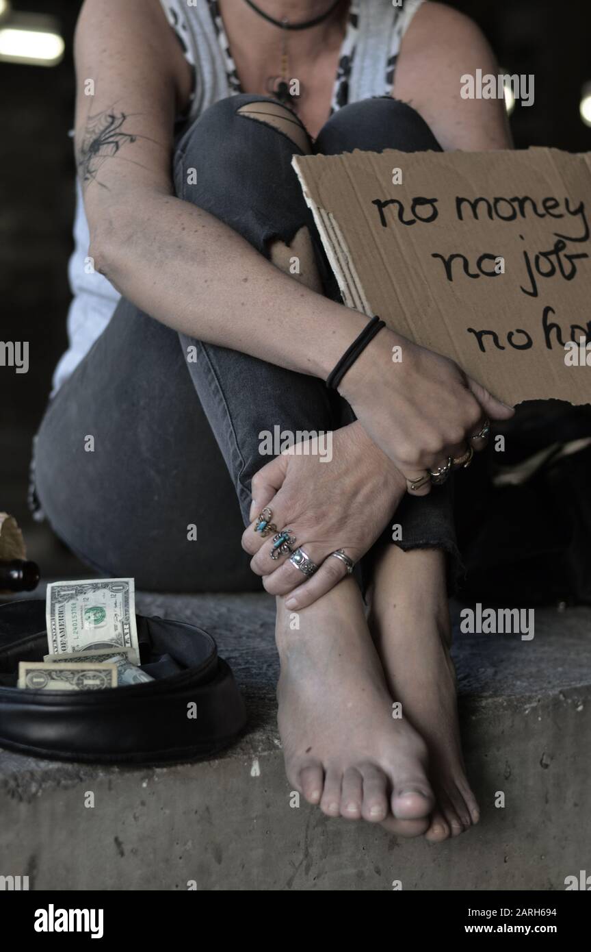 une femme sans abri punk la mendicité, tenant un signe - pas d'argent pas d'emploi pas d'espoir Banque D'Images