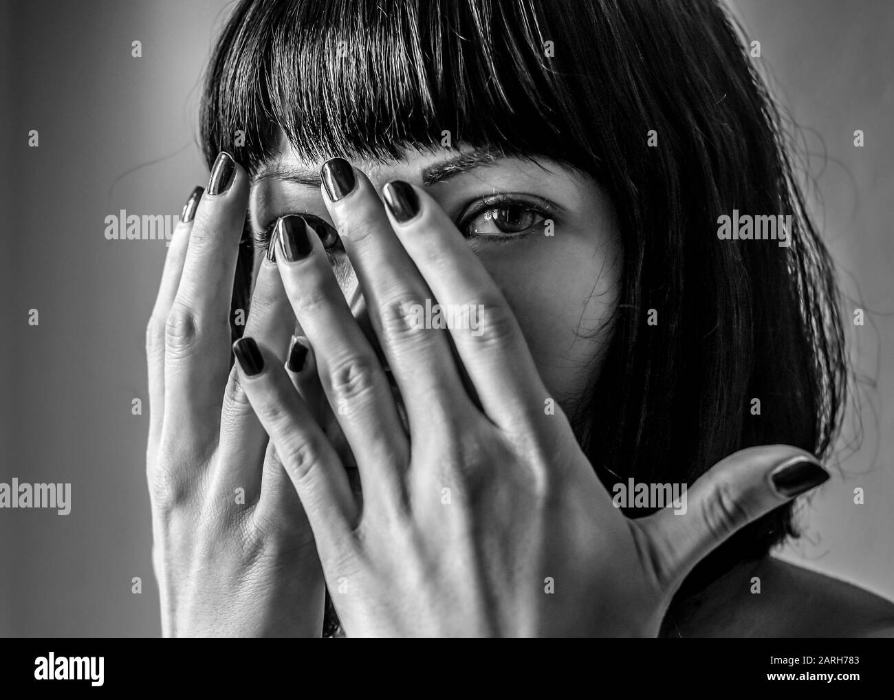 Portrait de la femme en noir et blanc se cachant face Banque D'Images