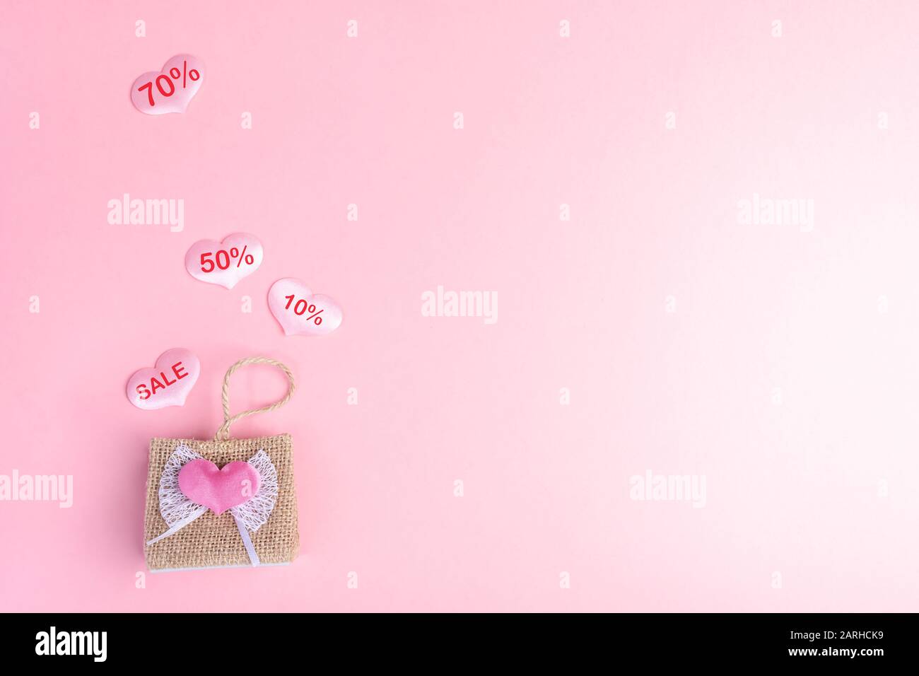Concept de Saint-Valentin. Achats et ventes de vacances. Petit sac à main décoratif en osier et quatre en son coeur rose avec des mots DE VENTE et de déconpays Banque D'Images