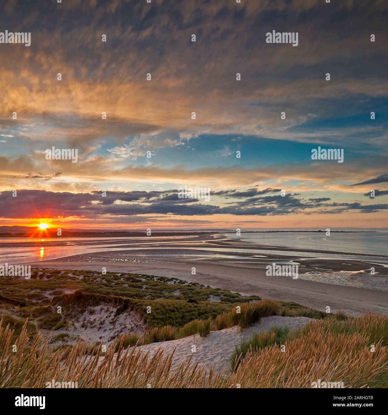 Coucher de soleil sur Budle Bay en direction de Lindisfarne près de Bamburgh, Northumberland, Angleterre, Royaume-Uni Banque D'Images