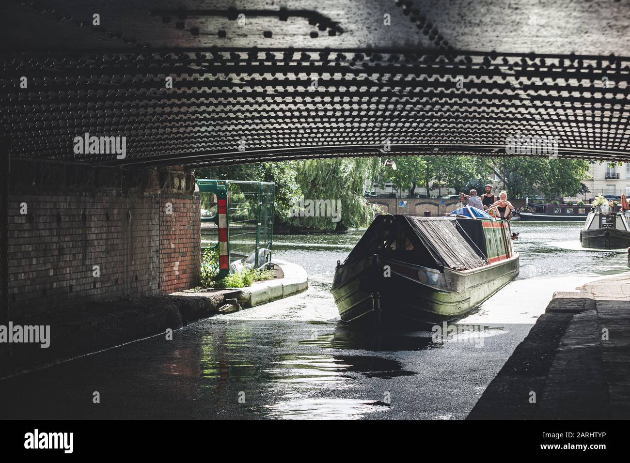 Londres/UK - 17/07/2019: Deux hommes, une femme et un chien sur la poupe d'un bateau à narrowboat naviguant sur le canal Regents sous le pont de l'avenue Warwick à Little Venice Banque D'Images