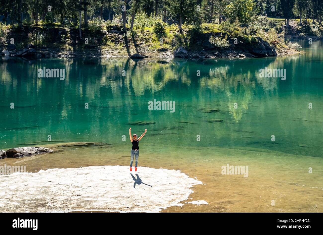Saut pour la joie d'être dans un endroit si étonnant, un lac vert incroyable dans les montagnes suisses. Banque D'Images