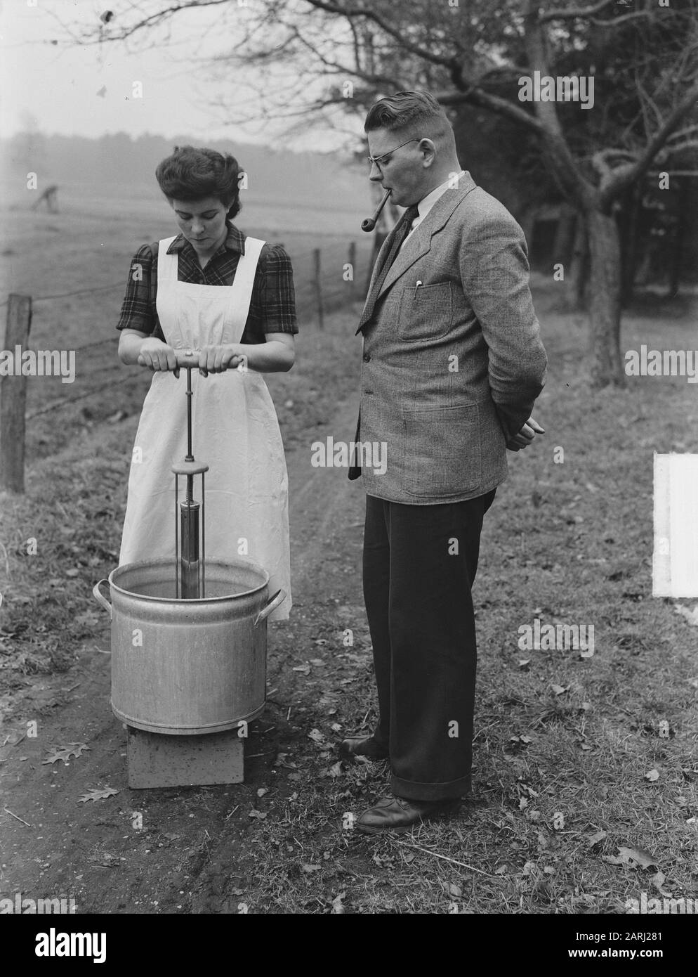 E. Koose du hameau de Joppe (près de Gorssel) a inventé un appareil avec lequel un linge normal peut être fait en 5 minutes. L'utilisation de cette solution coûte moins de savon et moins d'effort. Cette machine, qui ressemble à une pompe à vélo, n'est plus battue par l'eau savonneuse, mais le savon est battu par la cire. La femme de l'inventeur démontre la première pompe lave-linge Date: 30 janvier 1951 lieu: Gueldre, Joppe mots clés: Ménage, inventeurs, inventions, lavage Nom personnel: Cours, E. Banque D'Images
