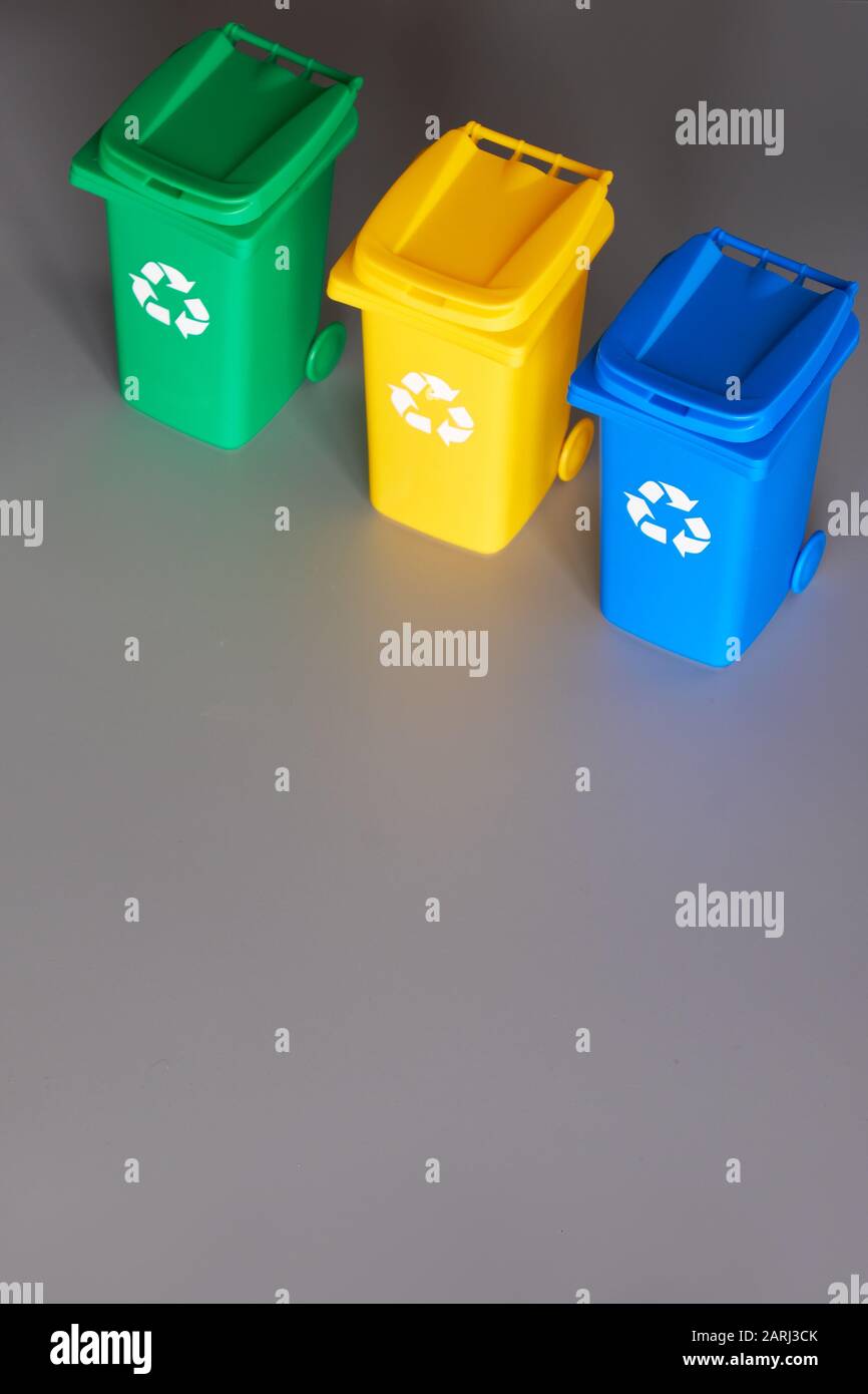 Trois bacs de recyclage à code couleur, image isométrique sur papier gris, espace de copie. Panneau de recyclage sur les bacs, bleu, jaune et vert. Séparation des déchets à r Banque D'Images