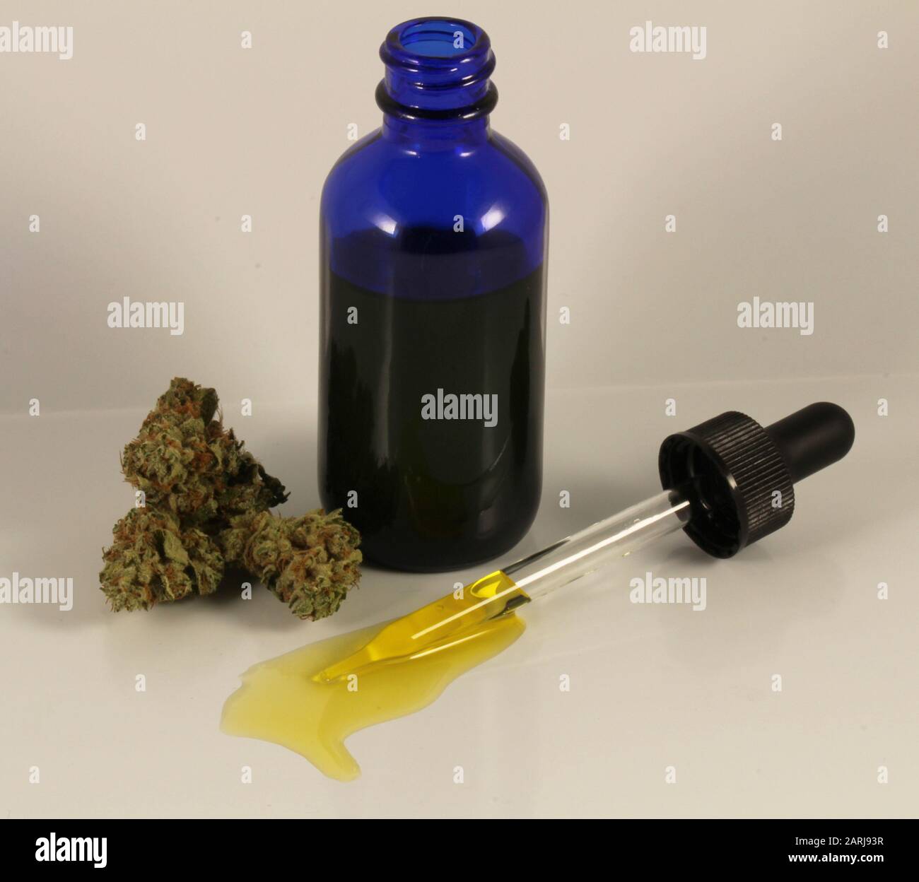 Huile CBD dans une bouteille de verre bleu avec pipette et fleurs Banque D'Images