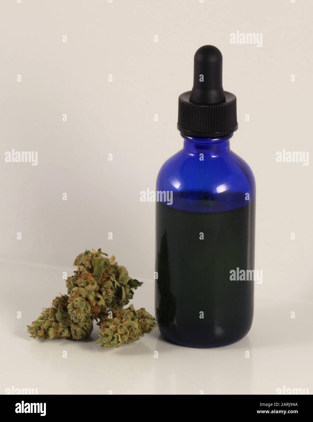 Huile CBD dans une bouteille de verre bleu avec pipette et fleurs Banque D'Images