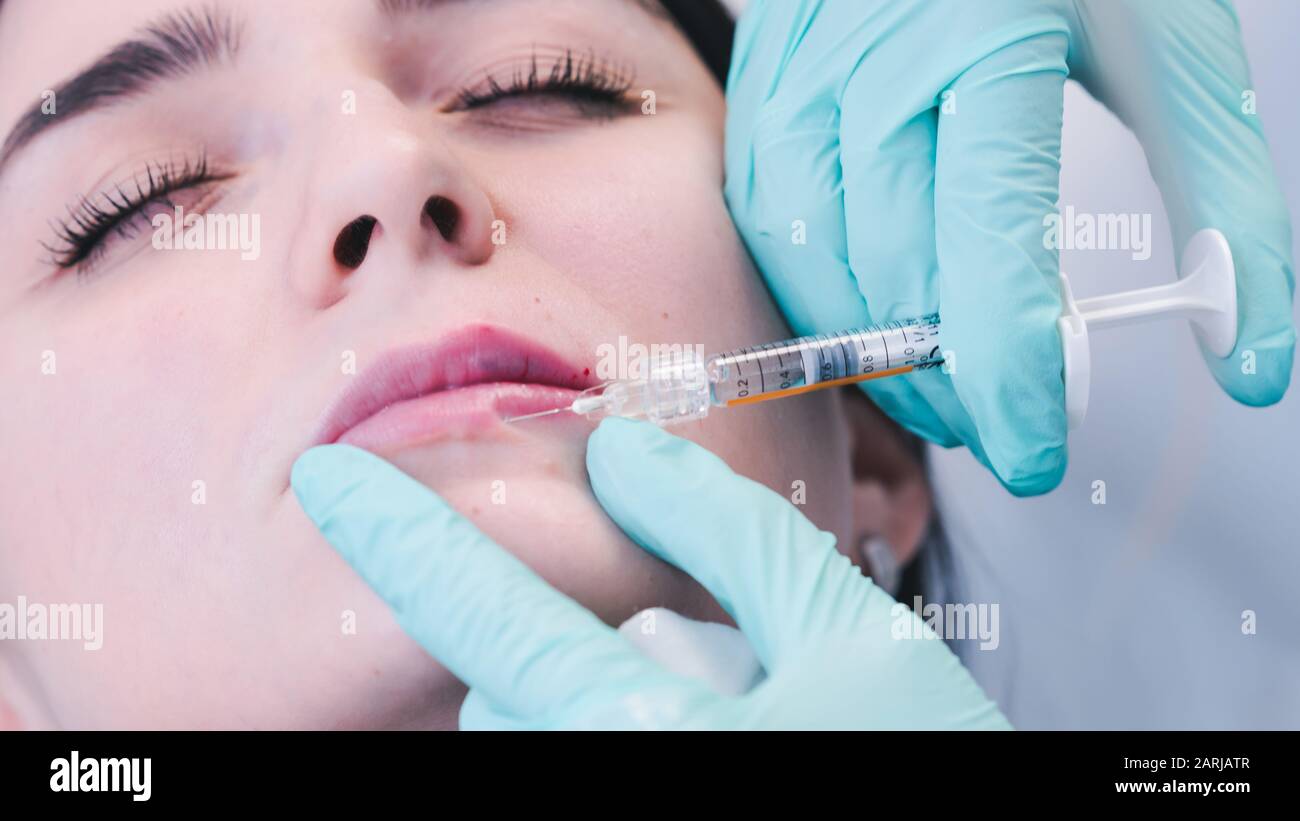 Les mains de l'esthéticienne font l'injection de botox dans les lèvres ...