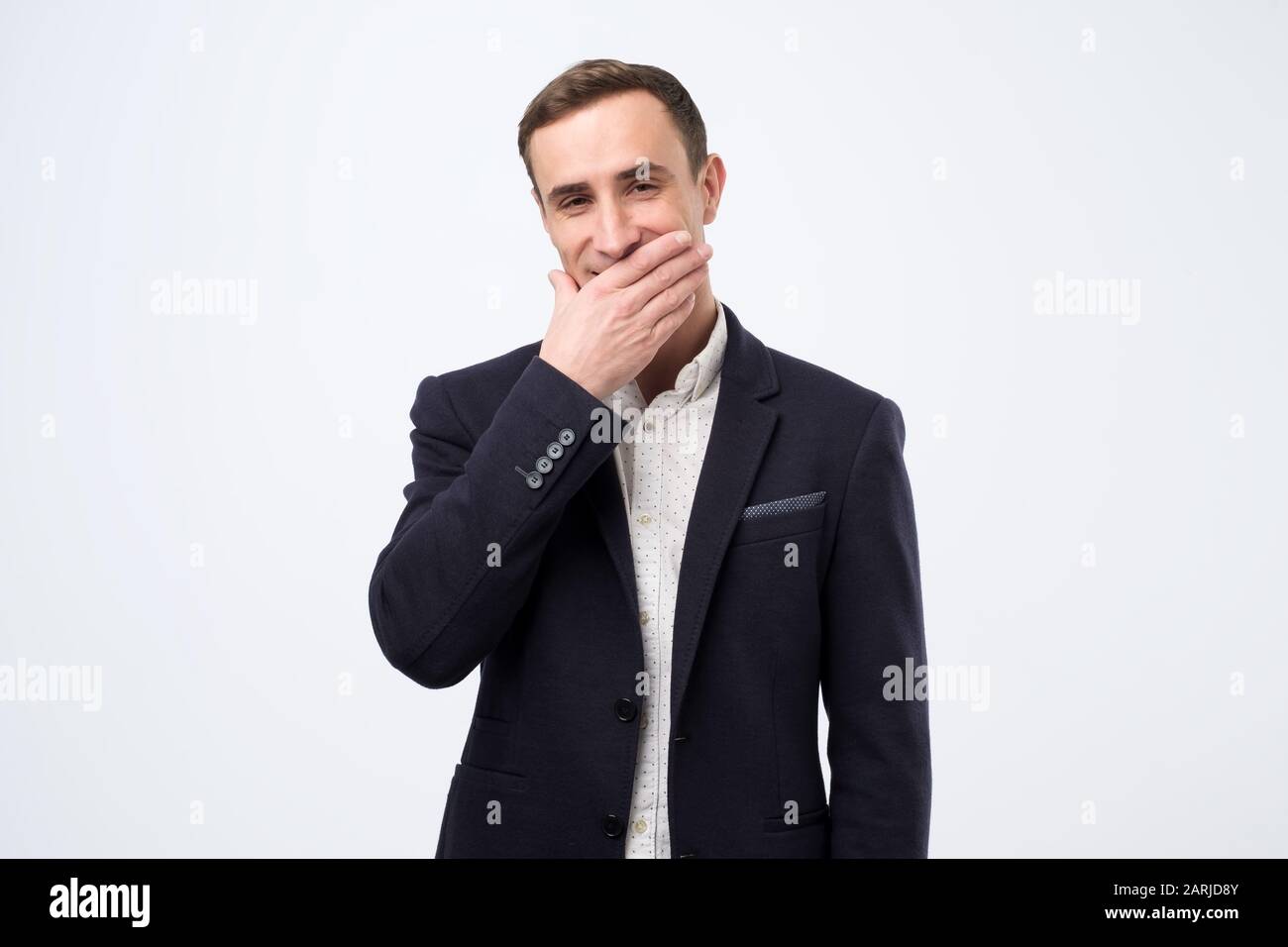 Des prix ridiculement bizarres. Homme caucasien gai riant et couvrant la bouche avec la paume, regarder la comédie ou entendre la plaisanterie drôle. Studio tourné Banque D'Images