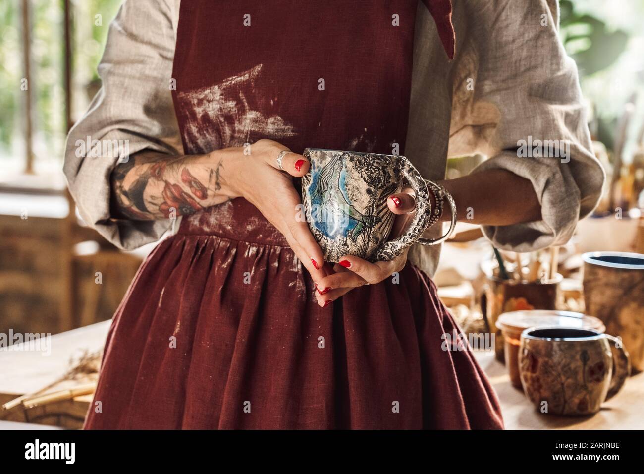 Artiste Concept. Jeune femme à l'intérieur avec la poterie fait main magnifique tasse close-up posant à l'appareil photo Banque D'Images
