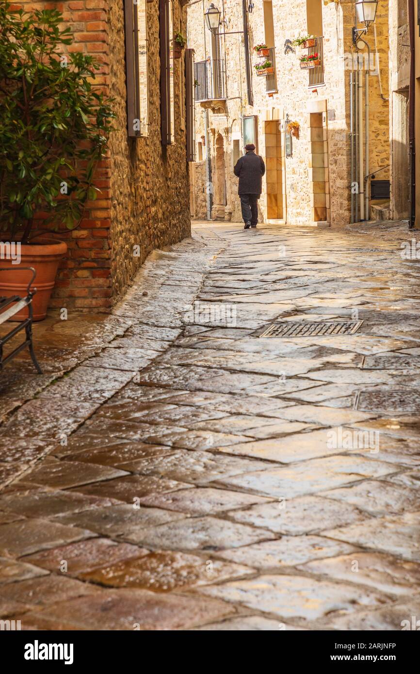 Italie, Sicile, Province De Palerme, Gangi. 12 Avril 2019. Un homme marchant dans la pluie sur une rue pavée à Gangi. Banque D'Images