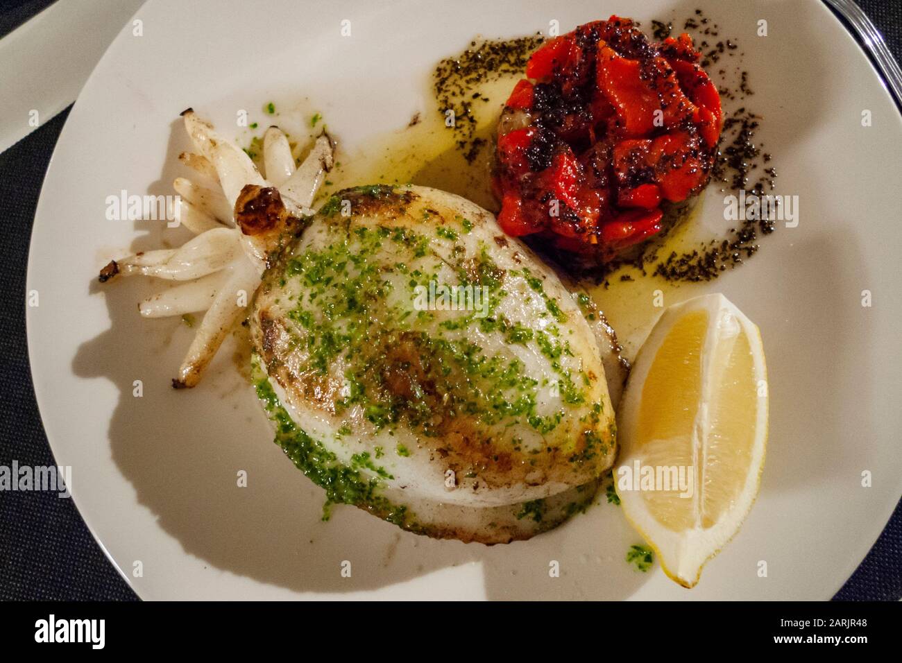 Une spécialité alimentaire locale est un poisson de viande entier servi avec une sauce au pesto et un poivron grillé. Altafulla, Catalogne, Espagne. Banque D'Images