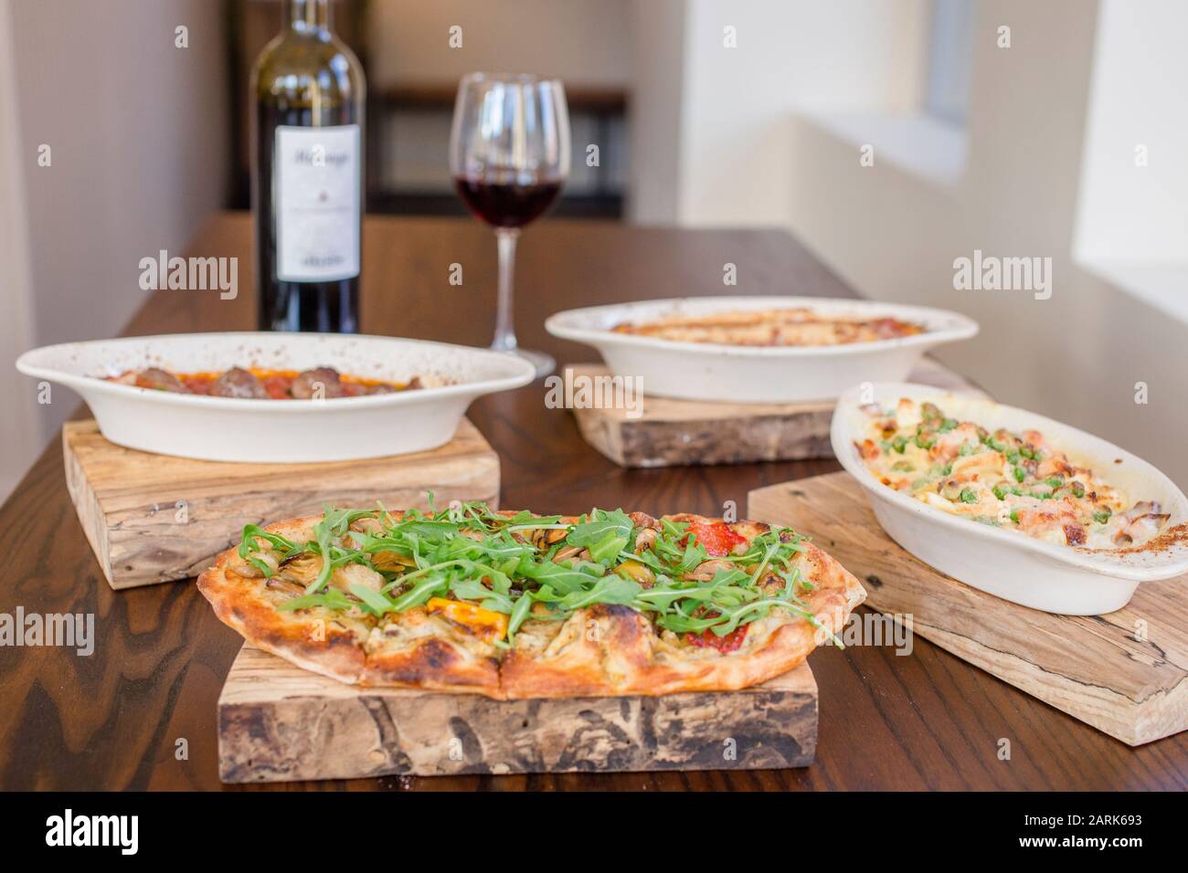 Une sélection de plats italiens se trouve sur une table avec une bouteille de vin rouge Banque D'Images