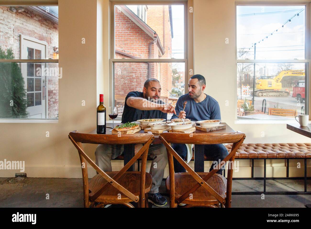 Deux hommes partagent un repas une bouteille de vin dans un restaurant vide Banque D'Images