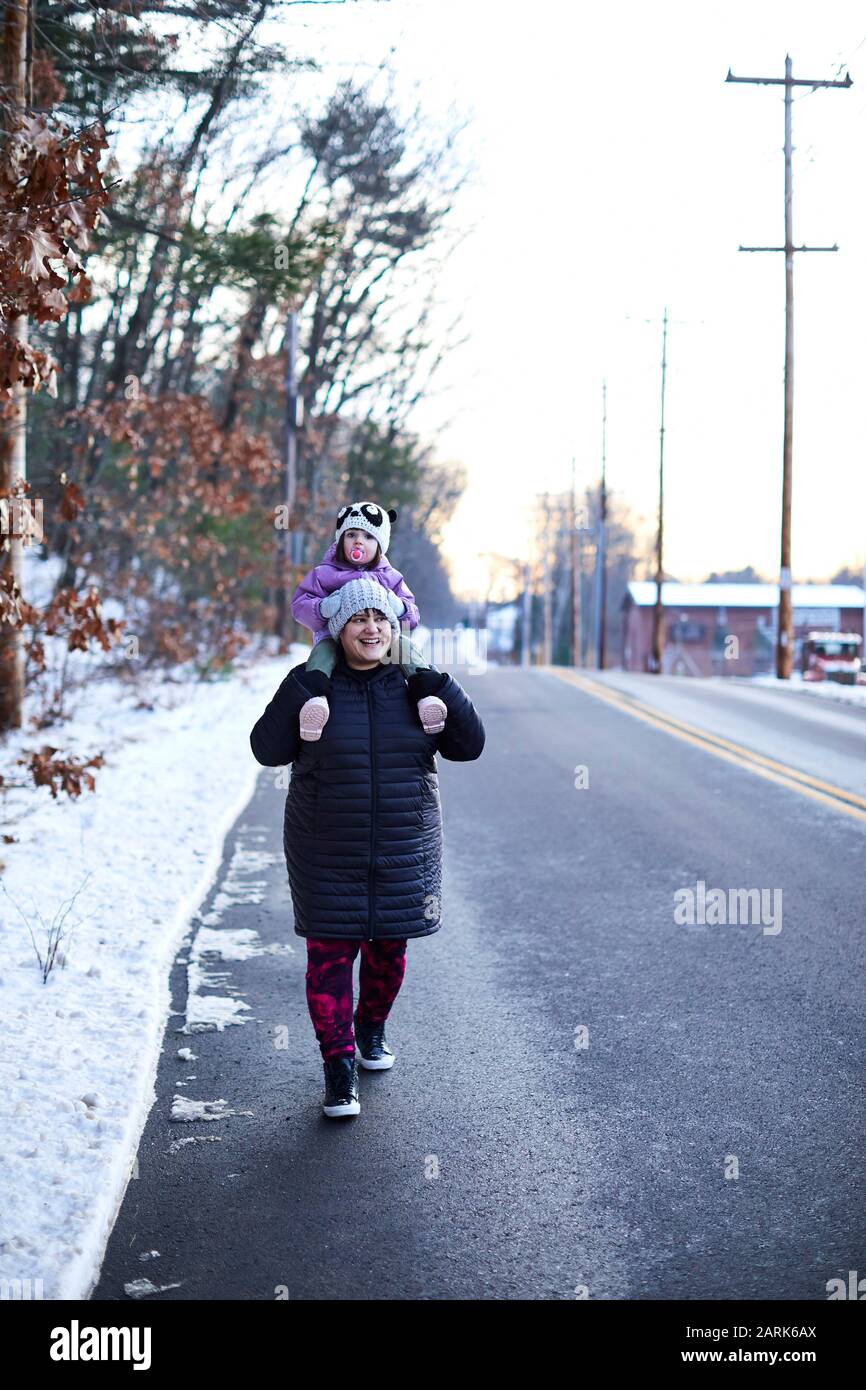 Petite fille sur les épaules de maman pendant une promenade d'hiver. Banque D'Images