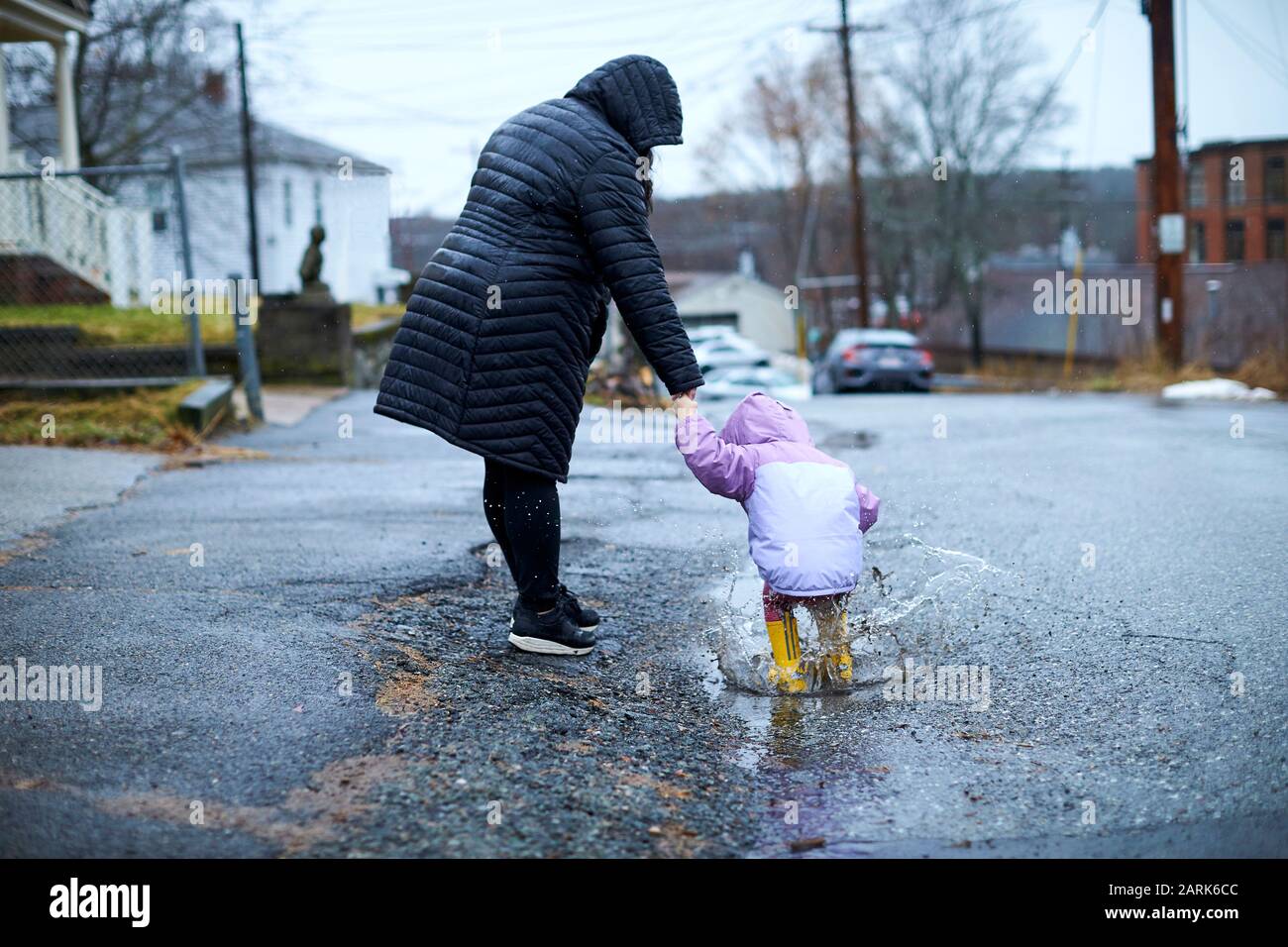 Une mère et un enfant qui s'amusent à barboter dans les flaques par temps pluvieux. Banque D'Images