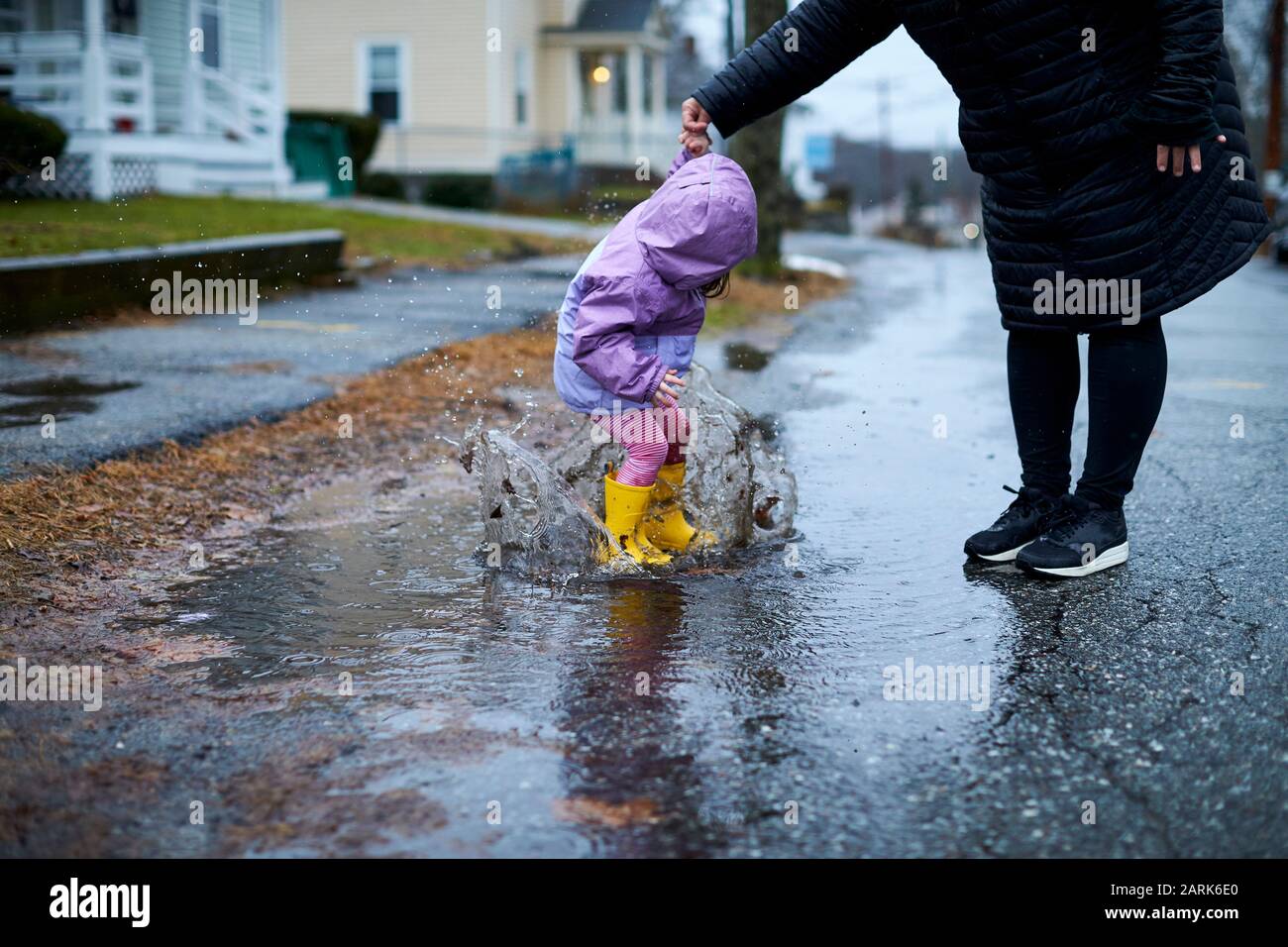 Une petite fille qui s'amuse à barboter dans les flaques par temps pluvieux. Banque D'Images