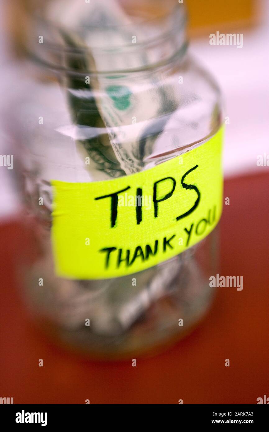 Toujours la vie d'un pot de pourboire avec des billets et des pièces de monnaie dans un restaurant local Banque D'Images