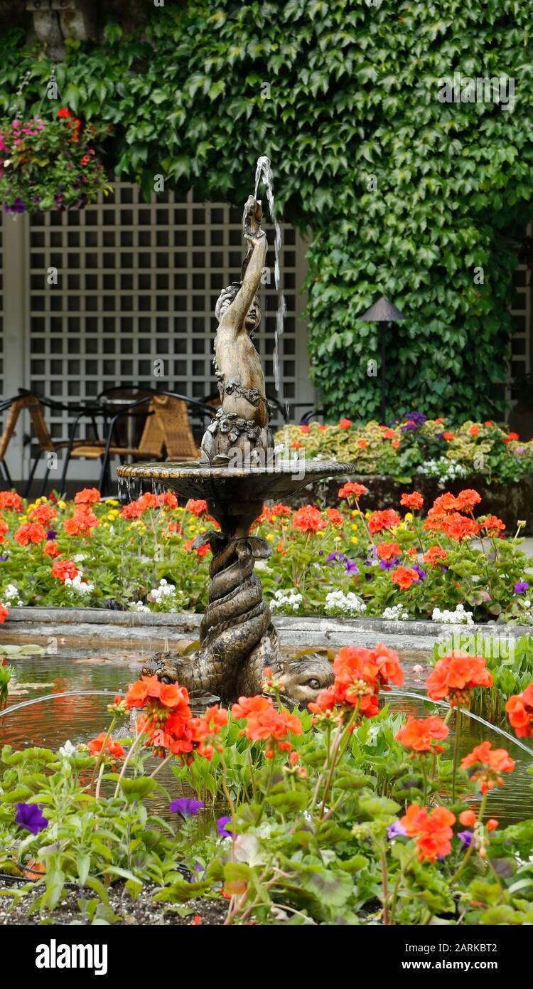 Une statue en bronze sert de fontaine dans un étang fleuri clouté dans le jardin italien des Butchart Gardens. Banque D'Images