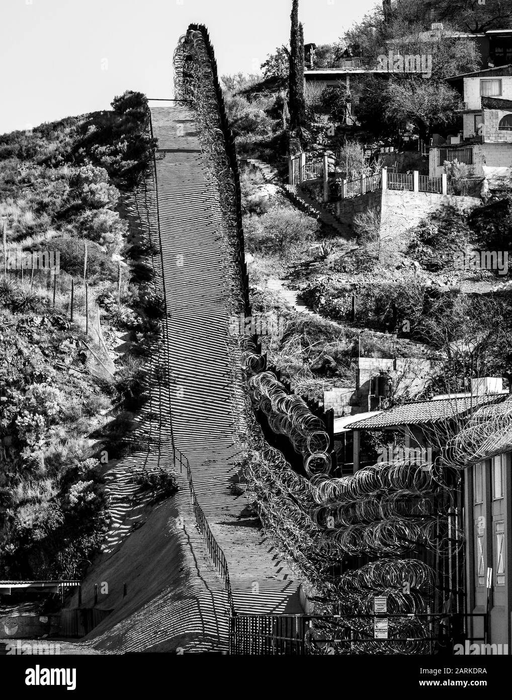 Vue de la clôture métallique des frontières internationales des États-Unis et du Mexique avec fil de rasoir en montant entre Nogales, Sonora, MX et Nogales, AZ, États-Unis Banque D'Images