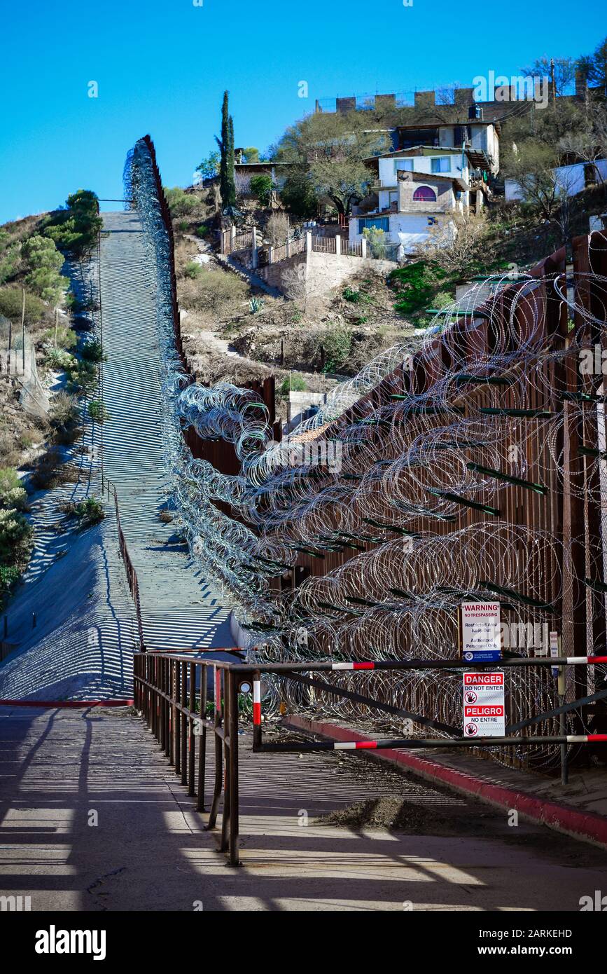 Vue de la clôture métallique des frontières internationales des États-Unis et du Mexique avec fil de rasoir en amont entre Nogales, AZ, USA et Nogales, Sonora, MX, Banque D'Images