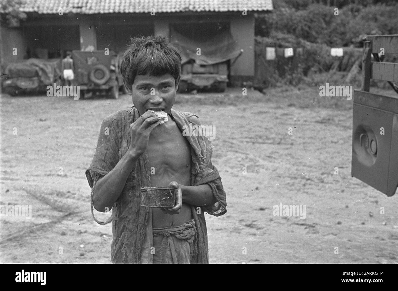 Photo Reportage Palembangs Mimmed indonésien homme mange sandwich et regarde dans sa main Date: Janvier 1947 lieu: Indonésie, Hollandais East Indies, Palembangs, Sumatra Banque D'Images