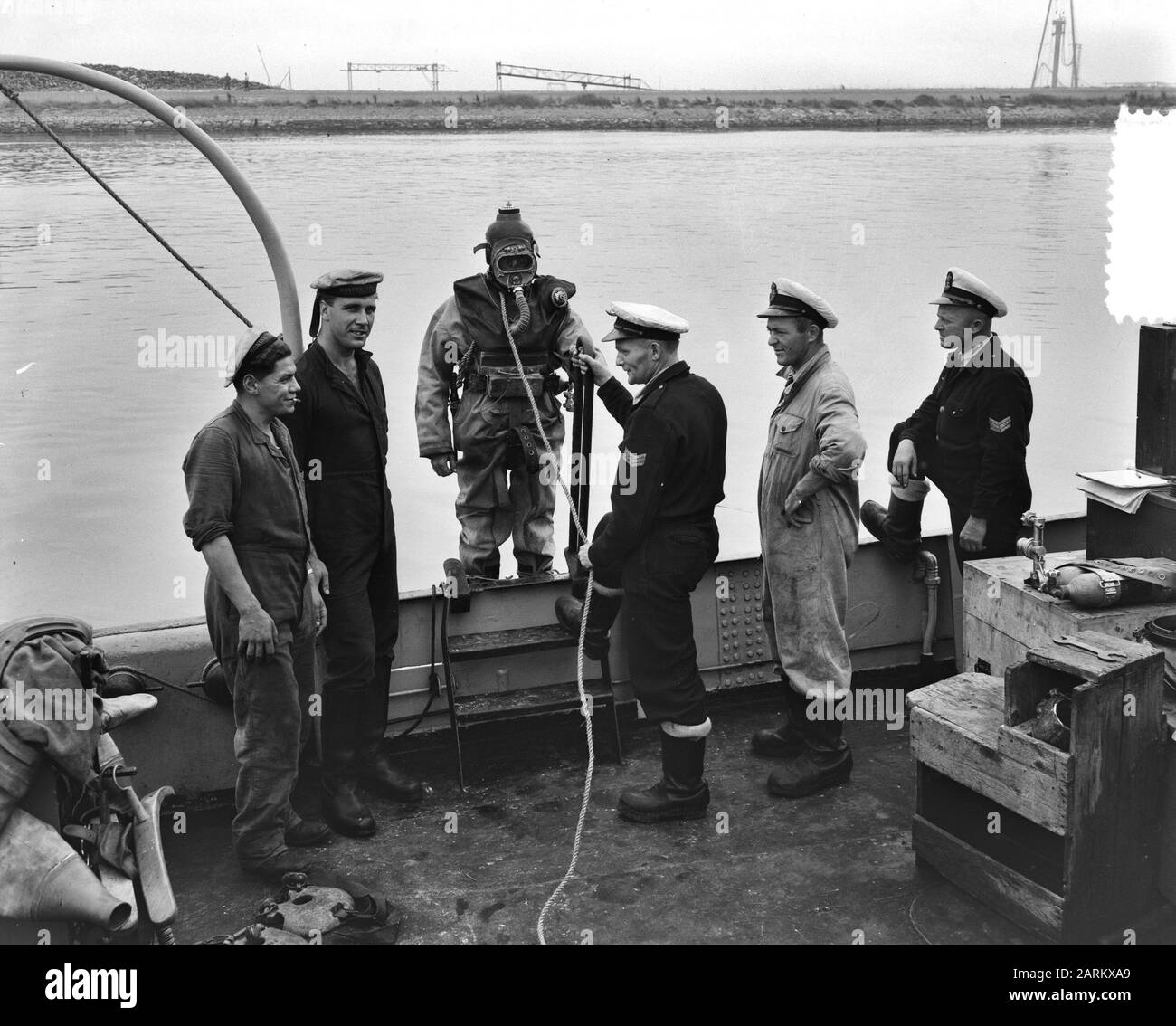 À Den Helder est pratiqué par le personnel naval belge pour l'entraînement au plongeur. L'un des Belges de plongée - un soi-disant costume de suivi, récemment utilisé par la marine néerlandaise - prêt à descendre du bateau d'entraînement de plongée. Complètement à droite l'un des autres Belges, qui est en formation pour plongeur Date: 12 septembre 1951 lieu: Den Helder, Noord-Holland mots clés: Plongeurs, marine, formation Nom de l'institution: Marine Banque D'Images