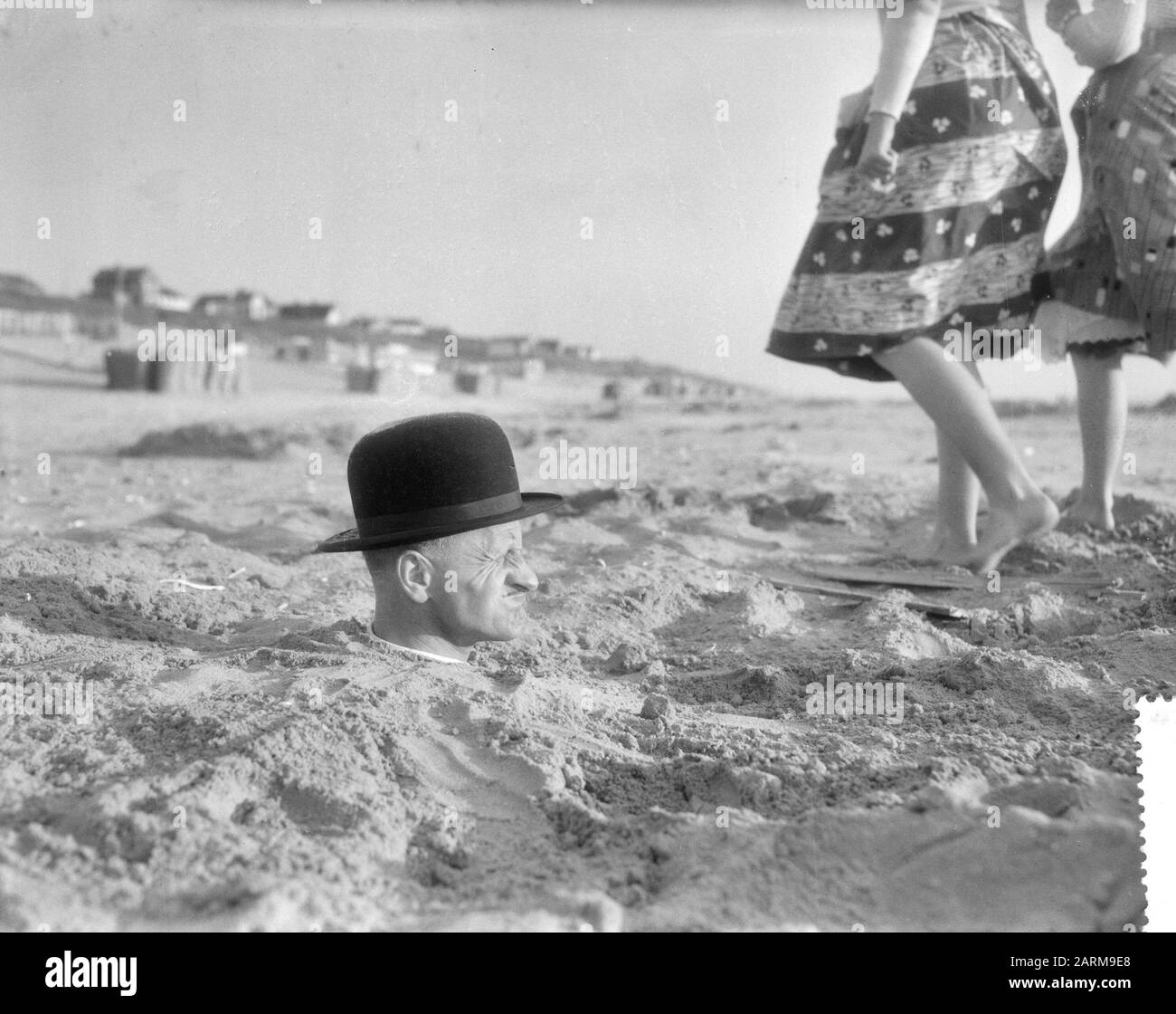 Situation étrange à la plage néerlandaise, homme avec corps entier dans le sable Date: 25 mai 1959 Banque D'Images
