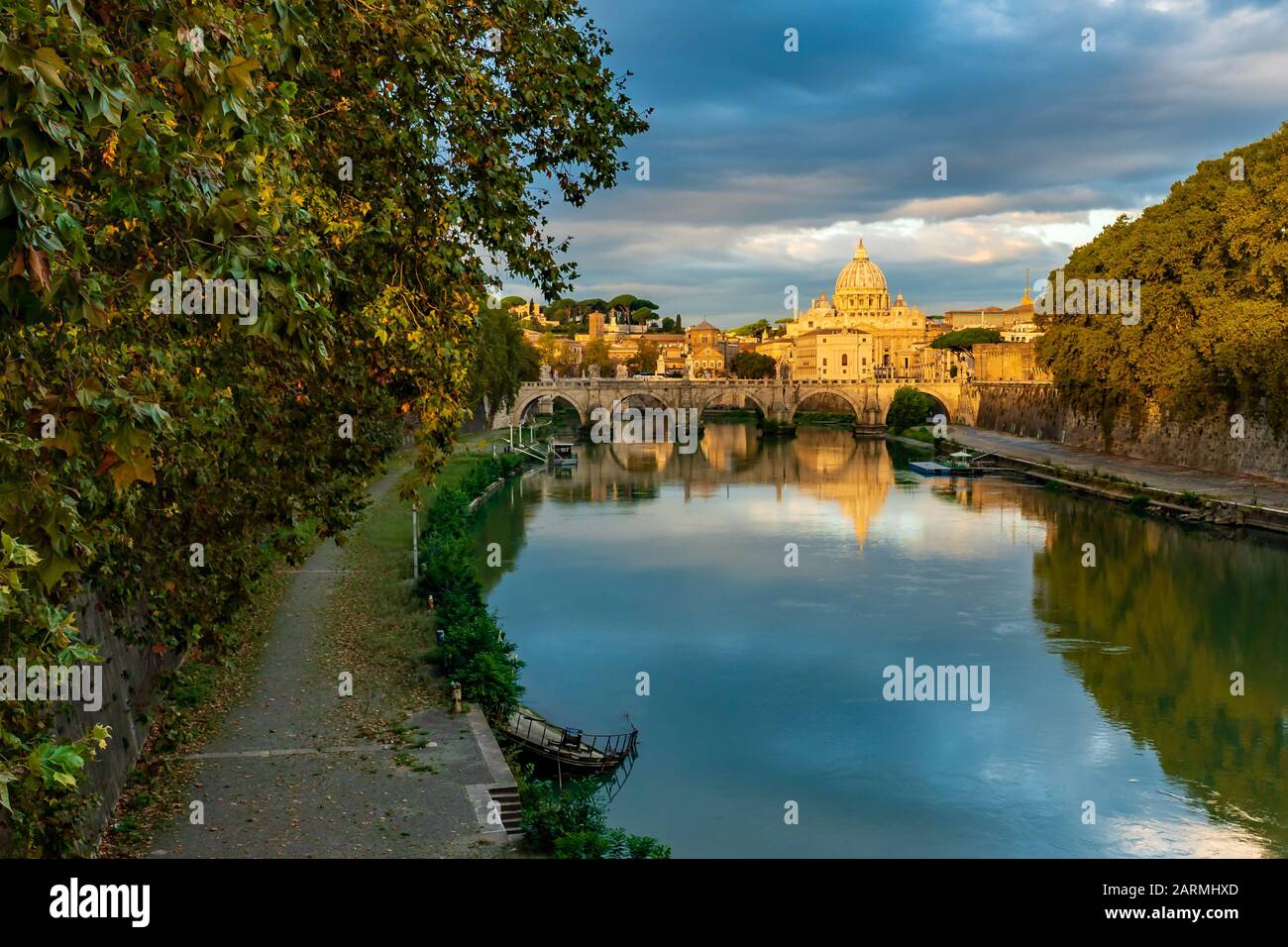 Vue sur le dôme de la basilique Saint-Pierre à Rome depuis un pont au-dessus du Tibre au coucher du soleil avec des couleurs et des reflets fantastiques dans l'eau, en Italie Banque D'Images