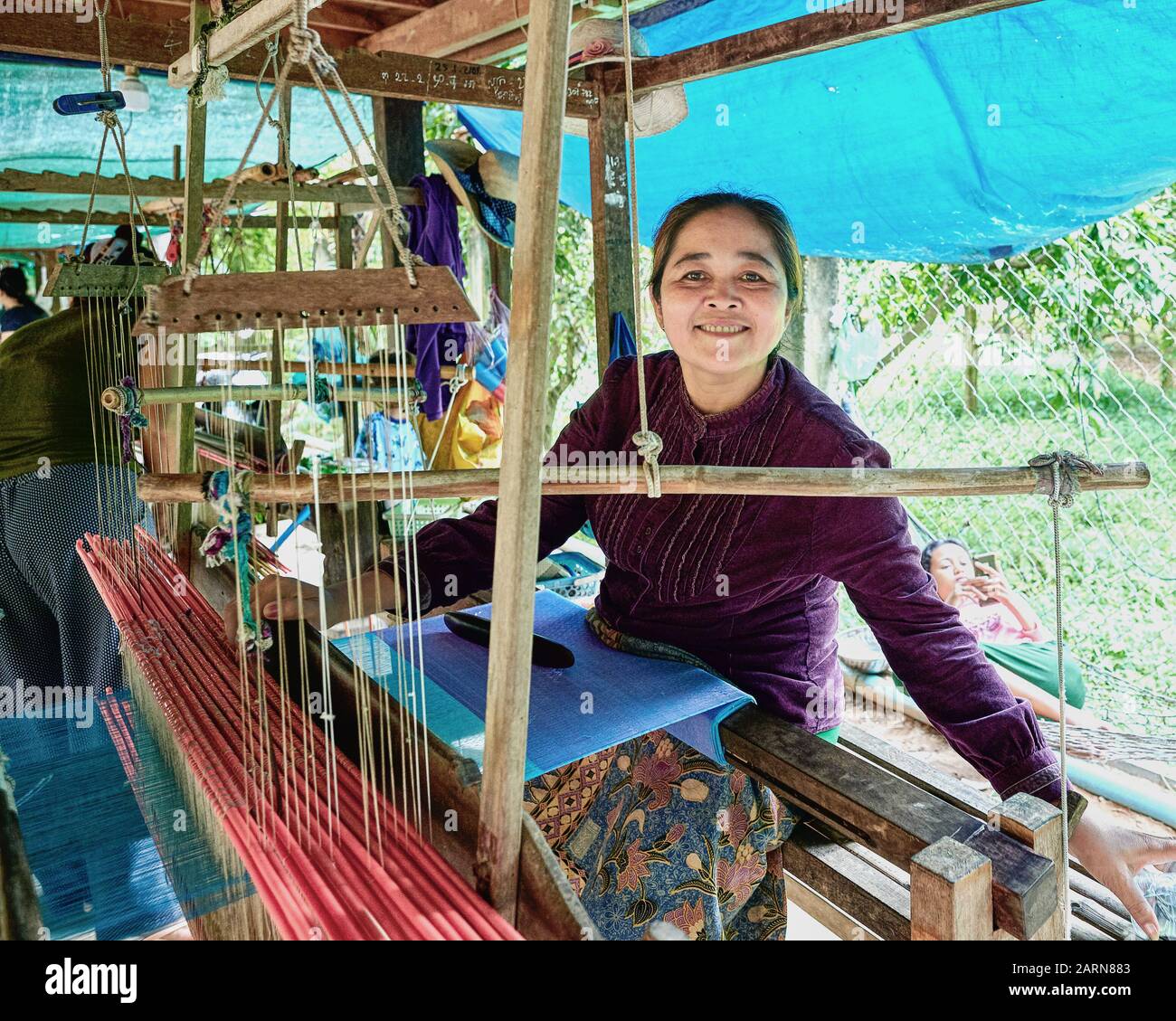 Les bobines de fil de soie sont insérées dans des navettes, qui sont utilisées sur des métiers en bois traditionnels pour tisser. Mère et fille à l'image. Banque D'Images