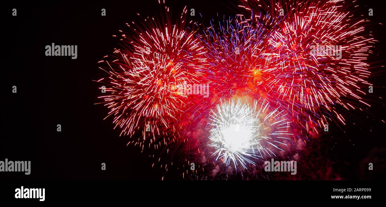 De grands feux d'artifice rouges, blancs, bleus et dorés en expansion ont été photographiés contre un ciel noir le 4 juillet au Minnesota Banque D'Images