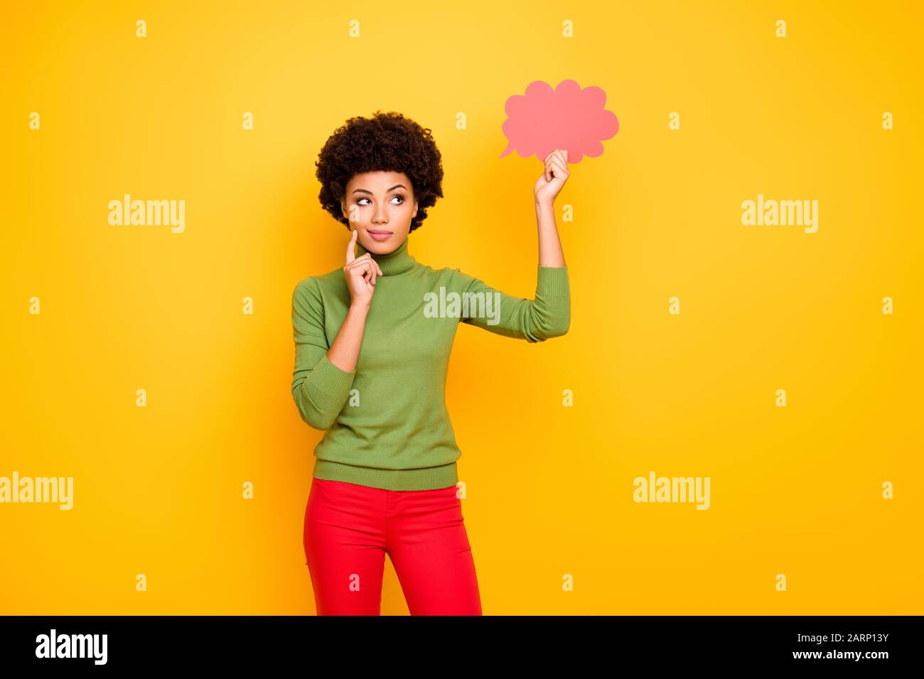 Photo de la pensée méditant la femme intéressée dans le pantalon rouge regardant dans le nuage rose de pensées pensant à de nouvelles idées isolé couleur de fond vibrante Banque D'Images