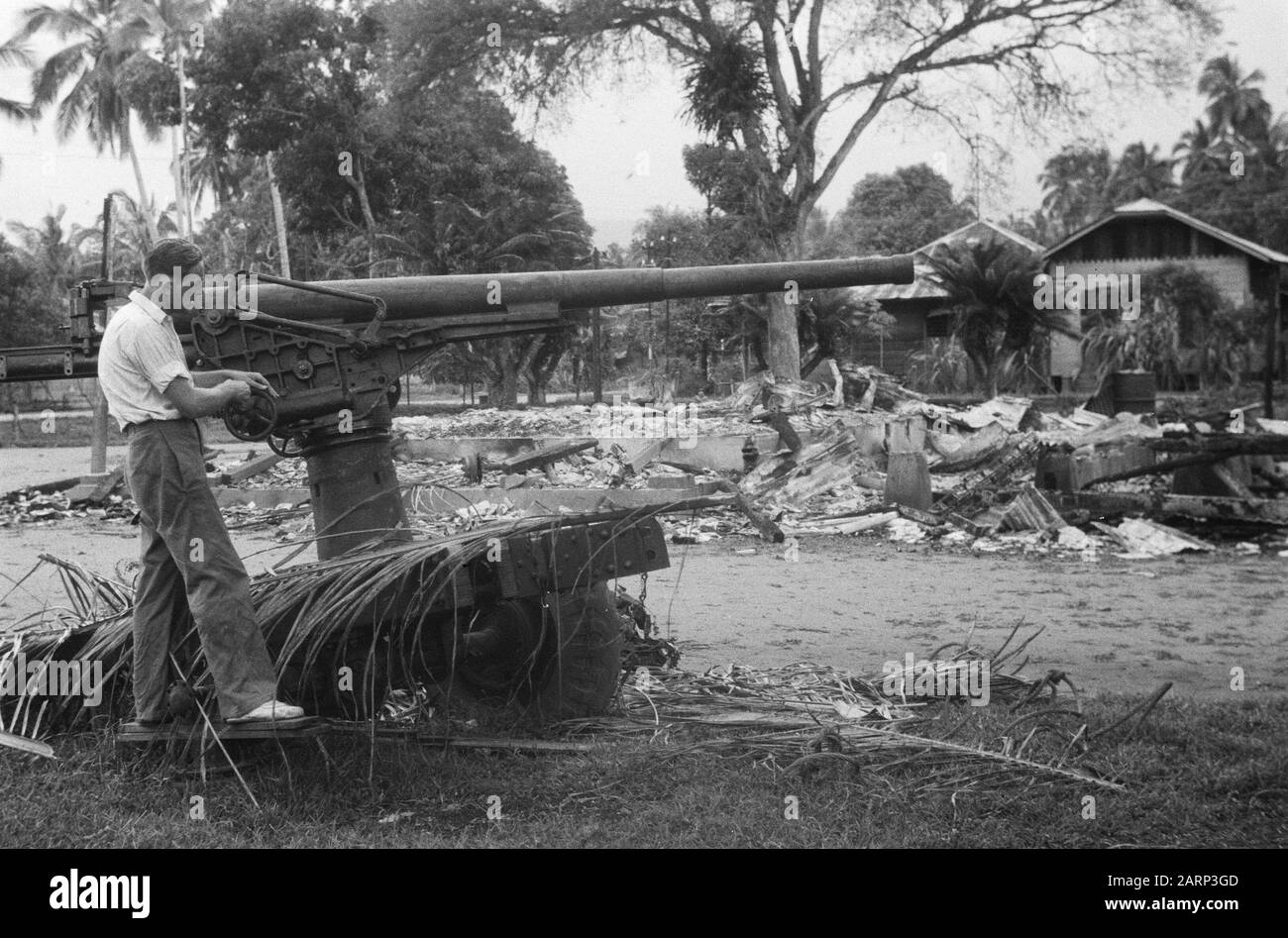 La marche de Tapanoeli, Tarutueng, Sibolga, Padang, Sidempoean Entre les dévastation est un homme européen en civil près d'un morceau abandonné (japonais?) fusil aérien Date: Décembre 1948 lieu: Indonésie, Hollandais East Indies, Sumatra Banque D'Images