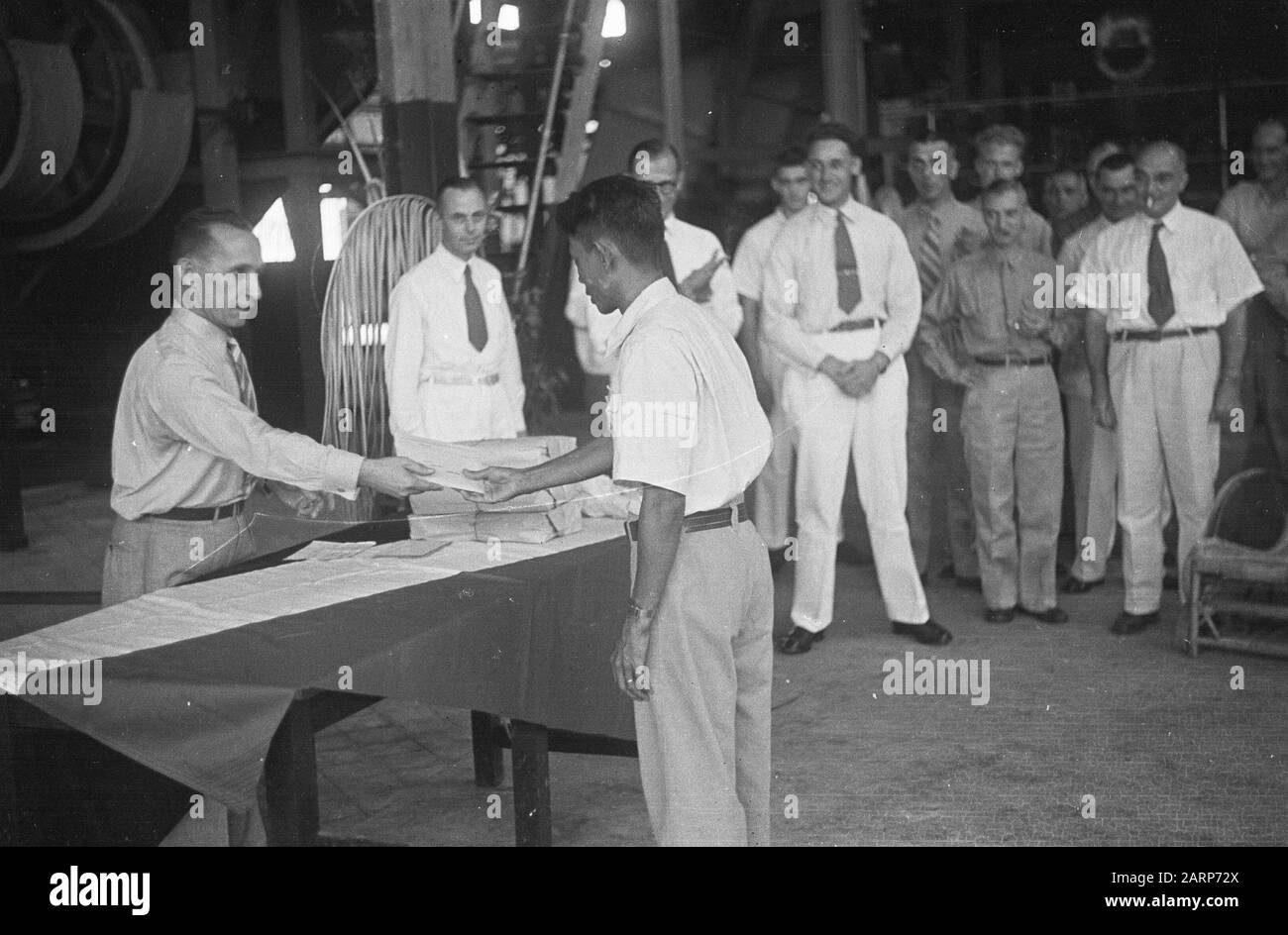 Un homme indonésien obtient quelque chose (un diplôme?) d'un homme en uniforme. Néerlandais hommes en citoyen et uniforme Date: 1947/01/01 lieu: Indonésie, Pays-Bas Indes orientales Banque D'Images